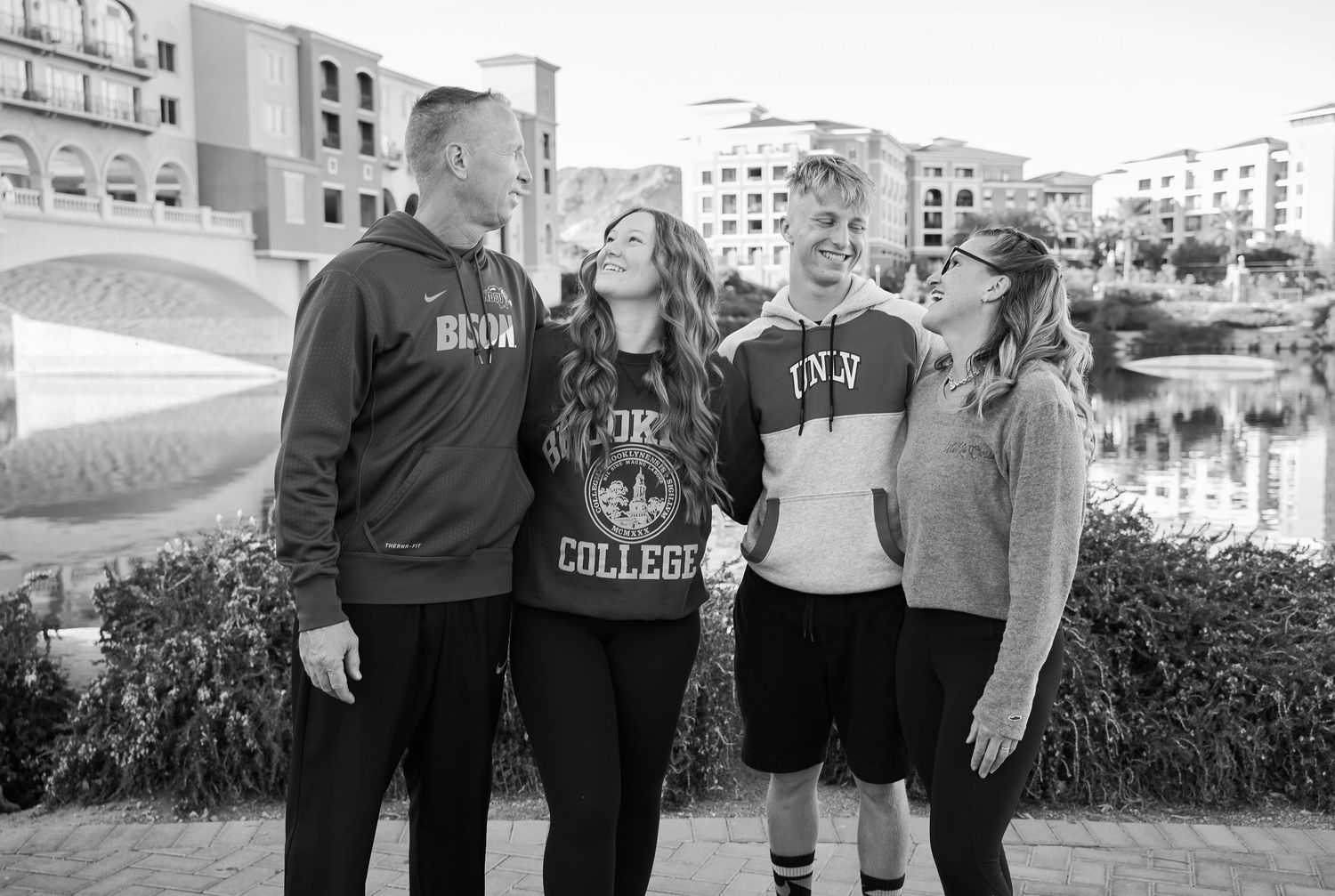A black and white photograph of students in athletic wear posing near a waterfront.