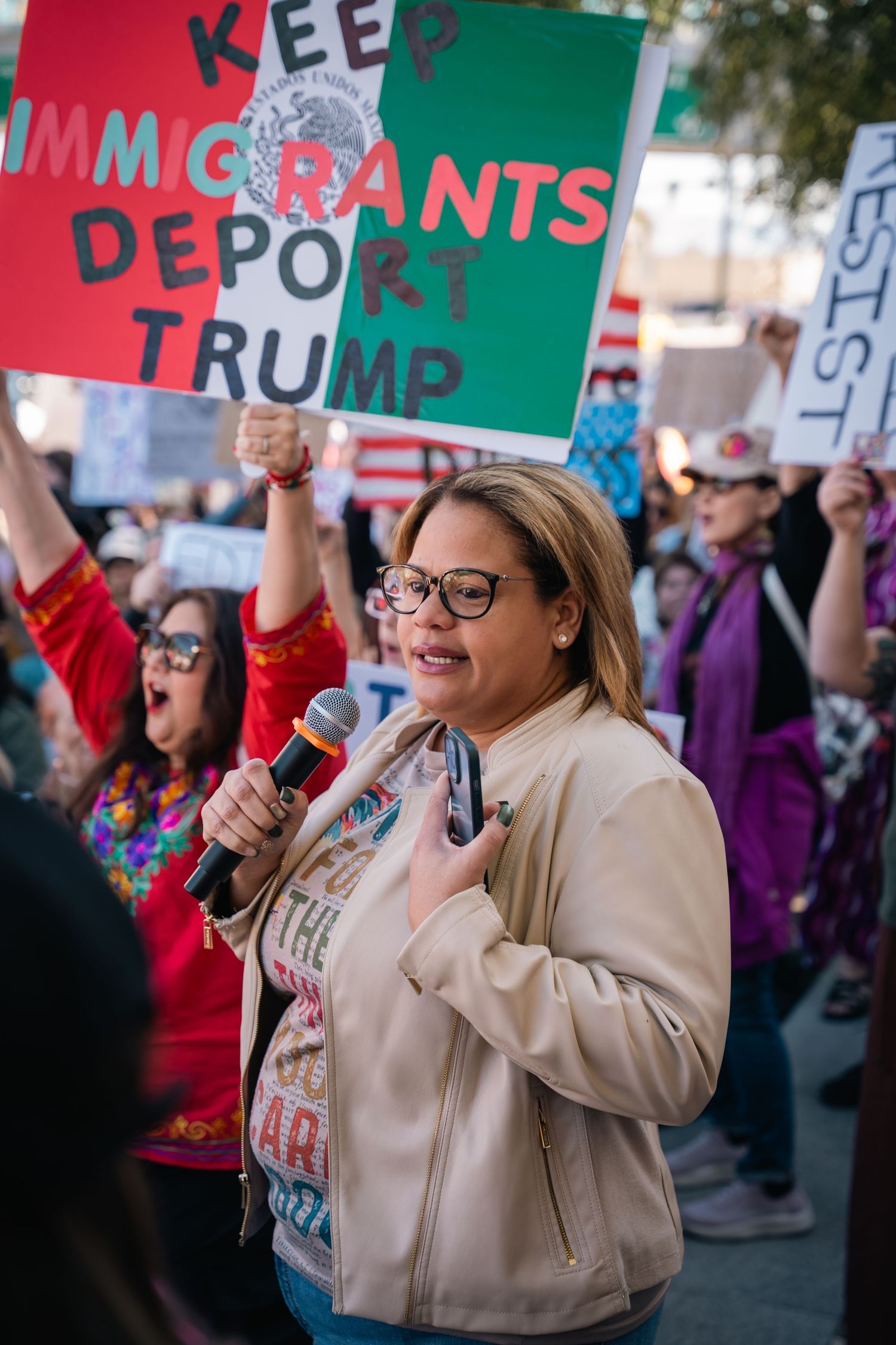 Protesters holding political signs at an outdoor rally.