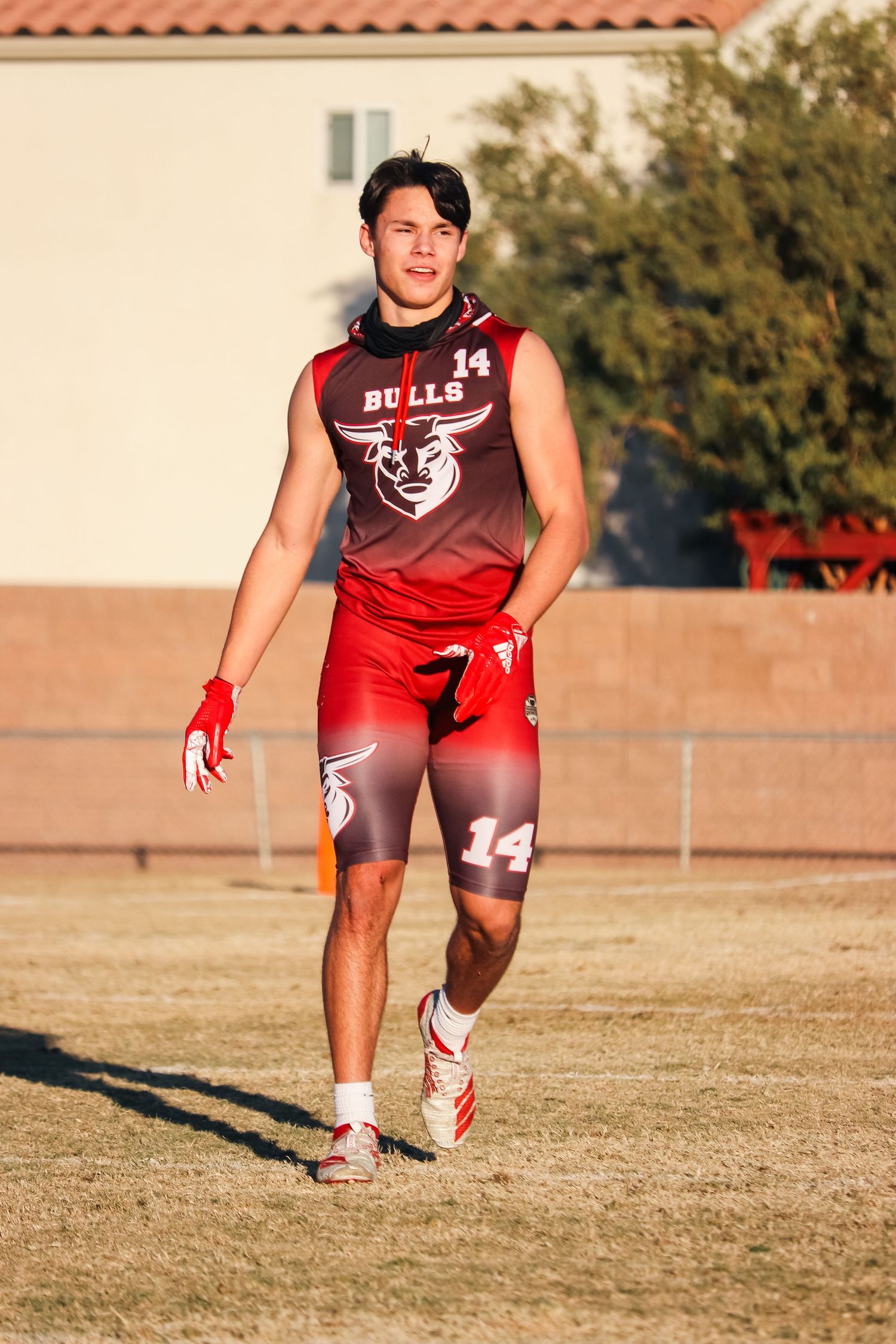 Football player in red and maroon uniform stands on grass field during game.