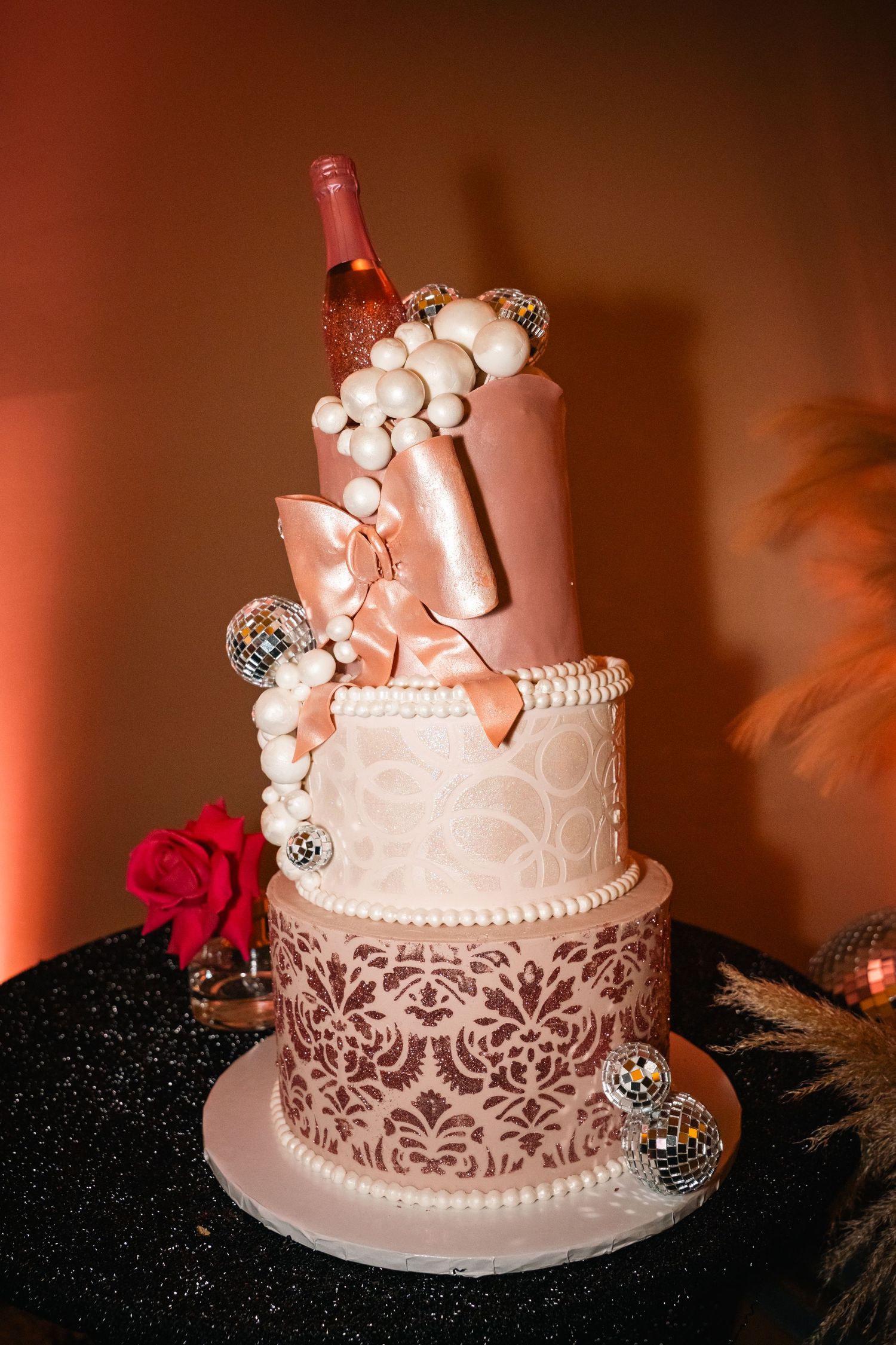 Elegant pink and white wedding cake with lace details and pearl decorations.