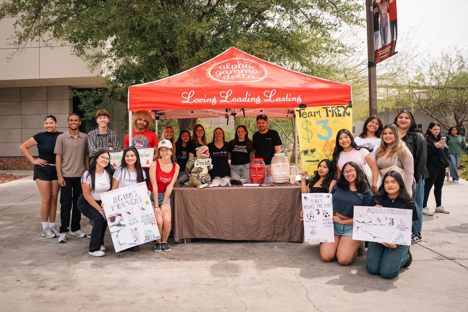 Students gather around a red tent and table display at an outdoor campus fair.