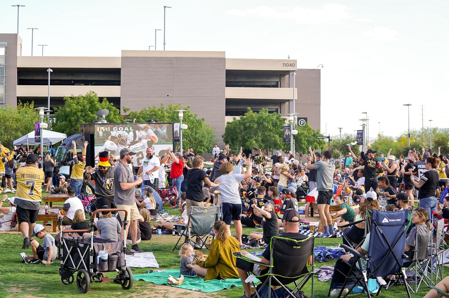 Large crowd of sports fans gathered outdoors with camping chairs and blankets.