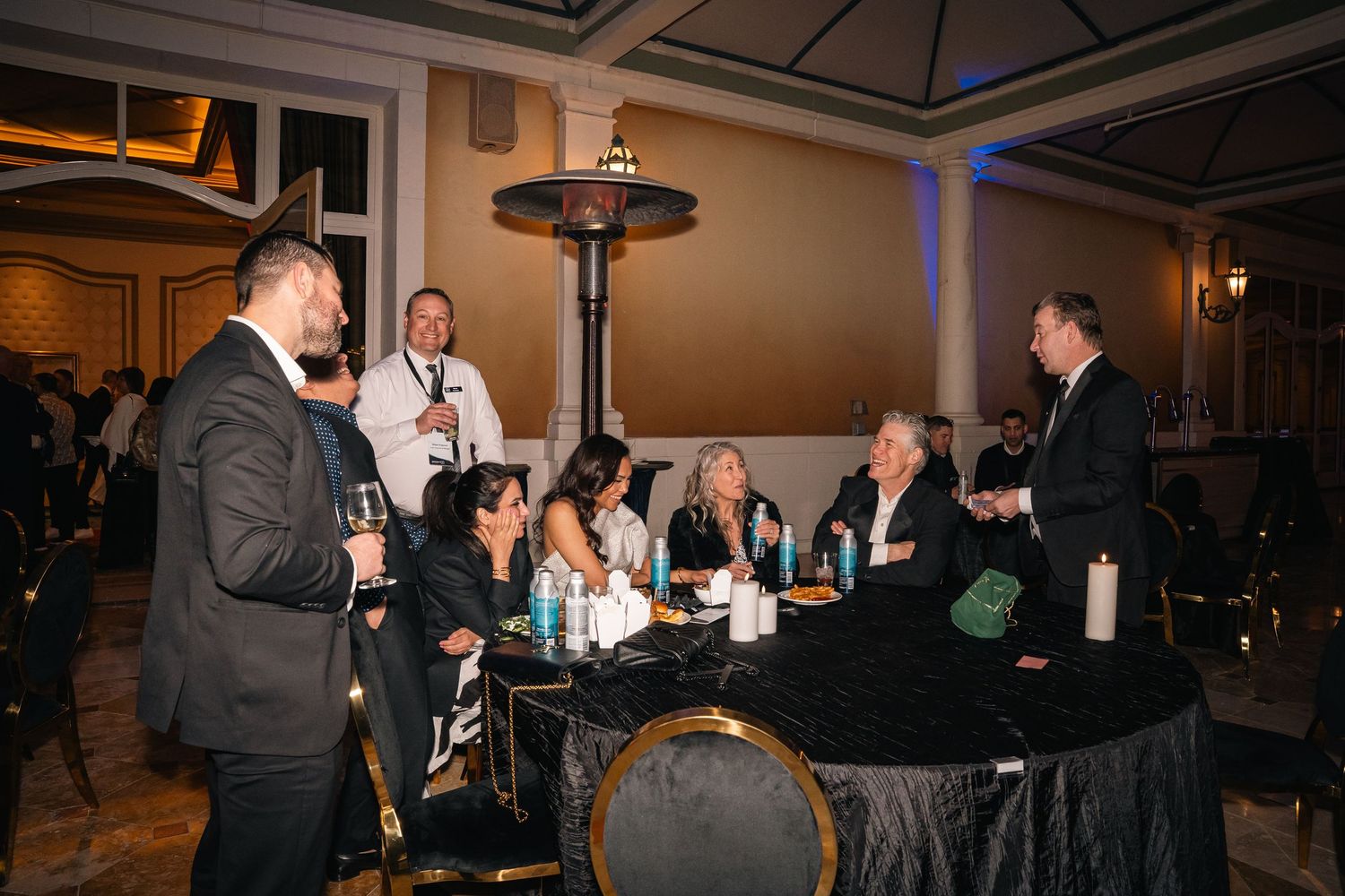 Business professionals gathered around table at upscale networking event with mood lighting.