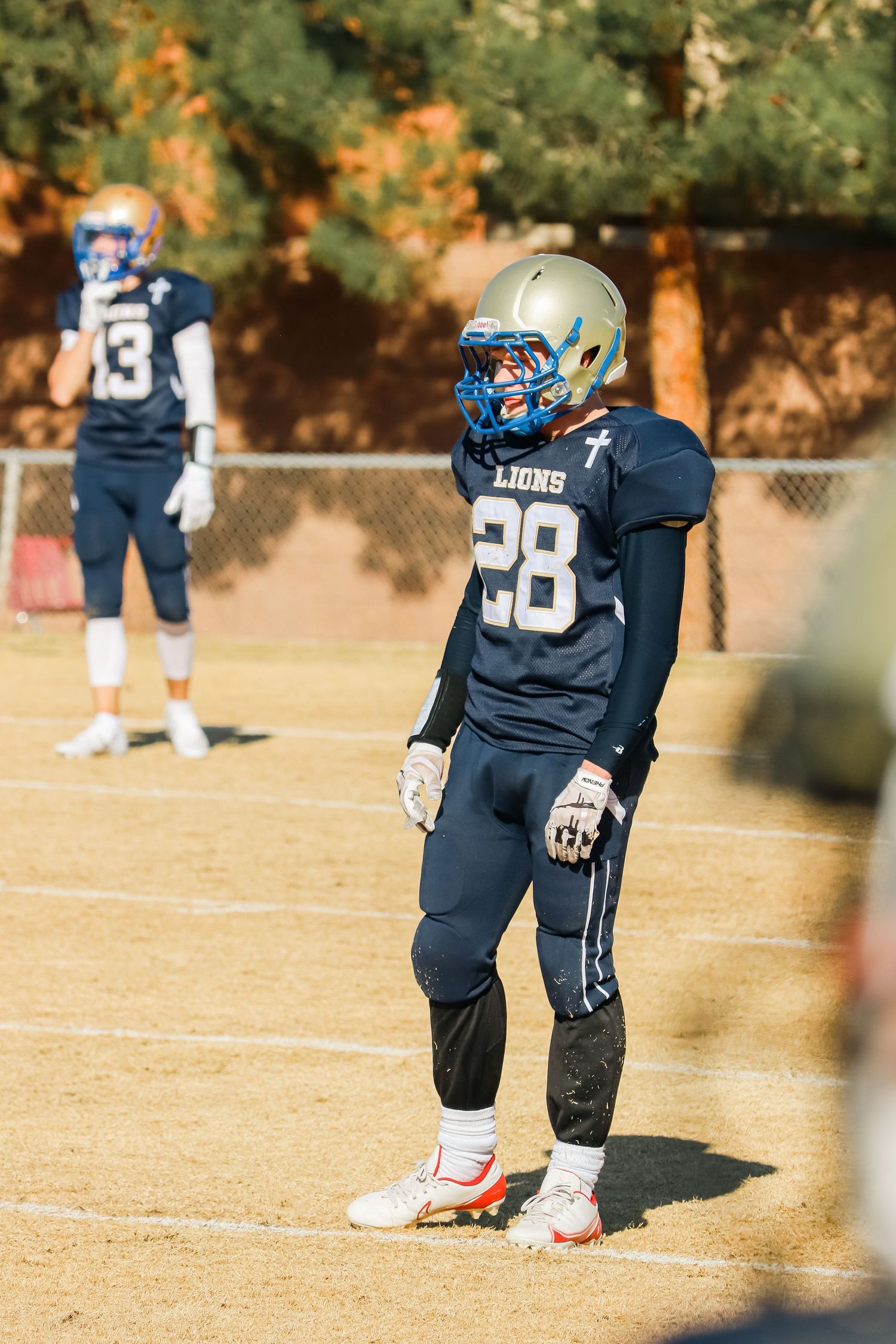 Football player in navy uniform with number 28 standing ready on field during game.