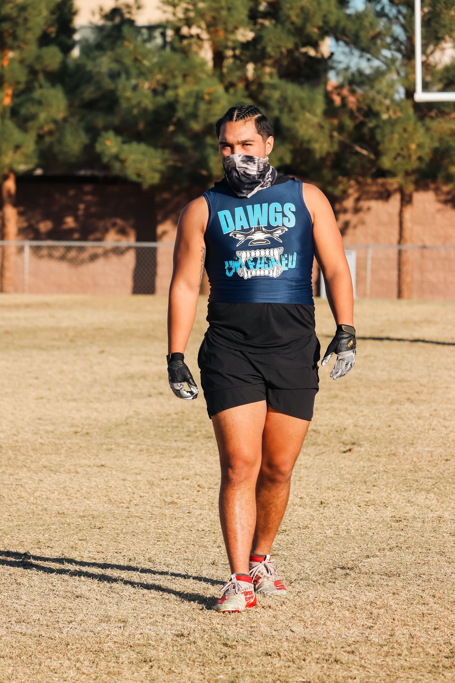 Player wearing Dawgs tank top and black shorts standing on practice field.