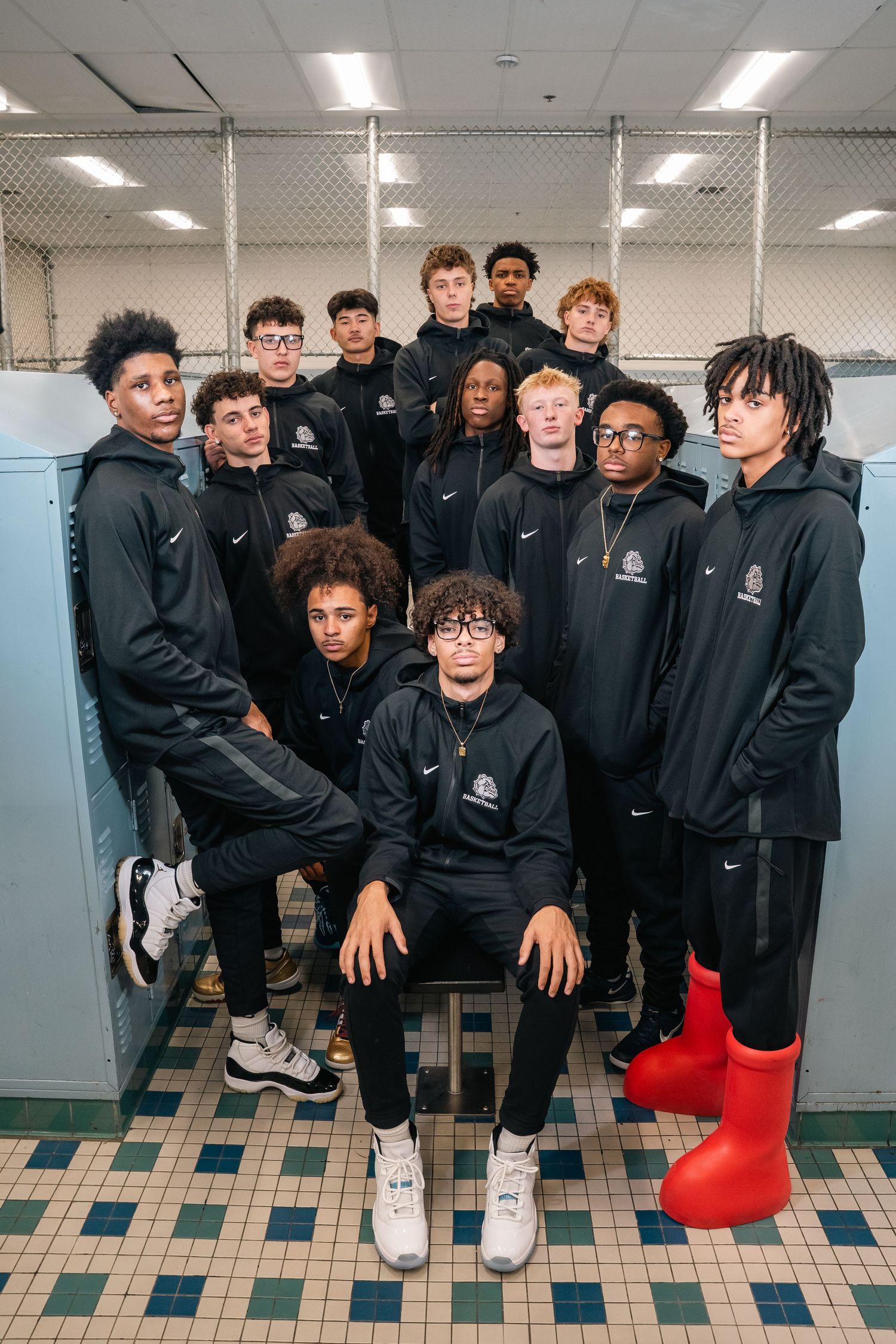 Basketball team members in black Nike hoodies pose together in locker room for group photo.