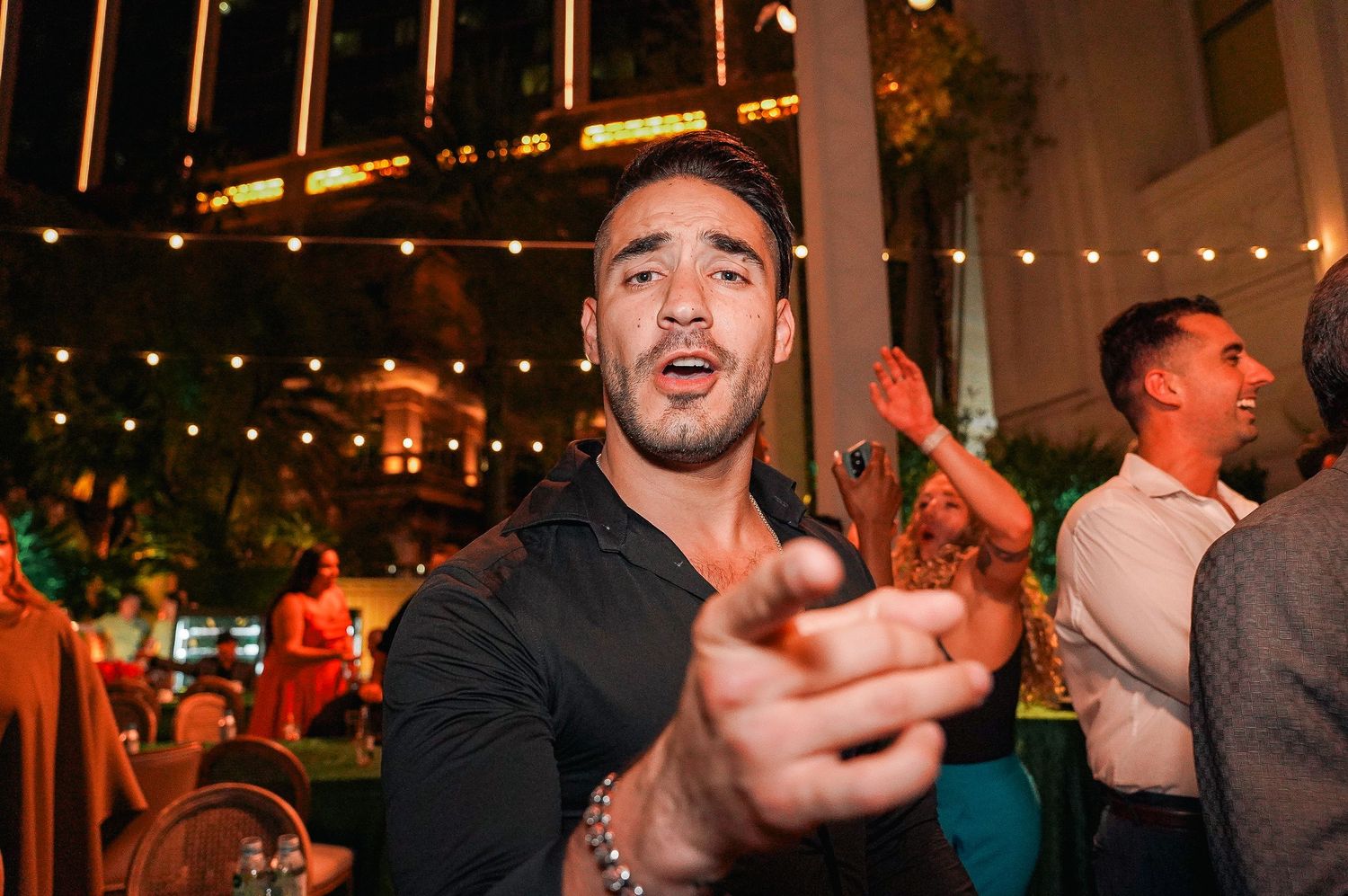 Party guest enjoying the celebration with animated expression at an outdoor evening event.