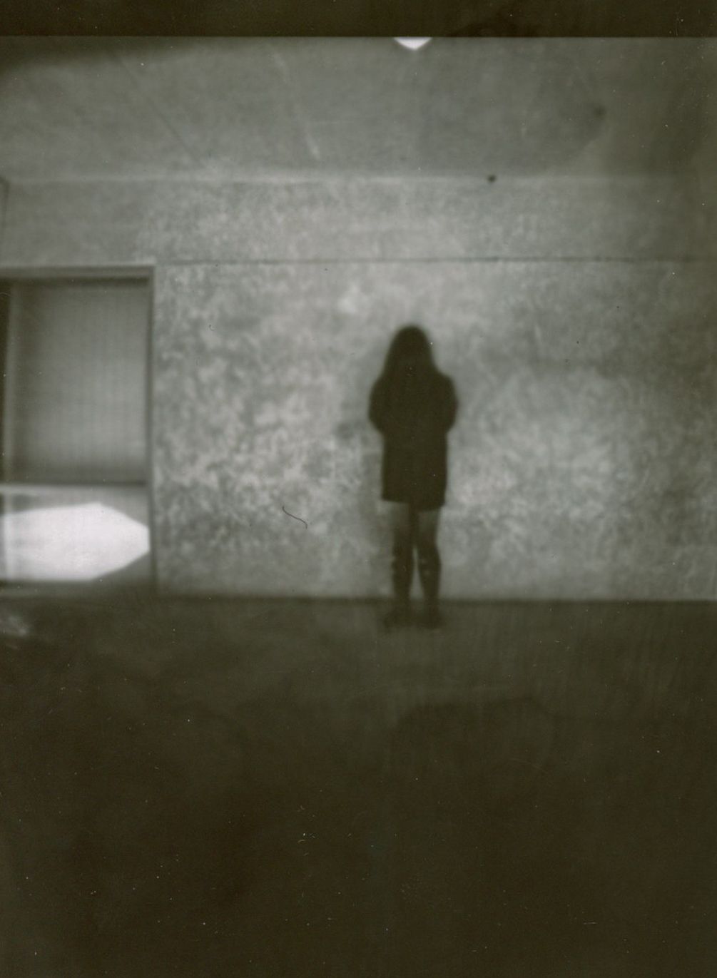 Atmospheric black and white photo showing silhouette against textured wall.