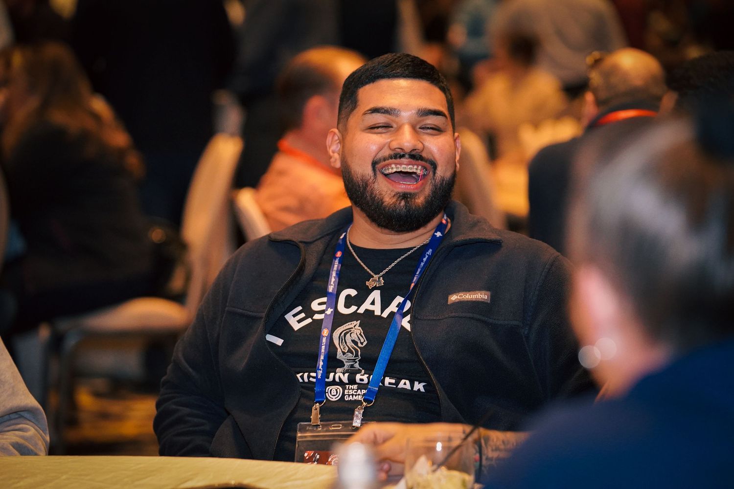Audience members smiling and engaging during an indoor event.