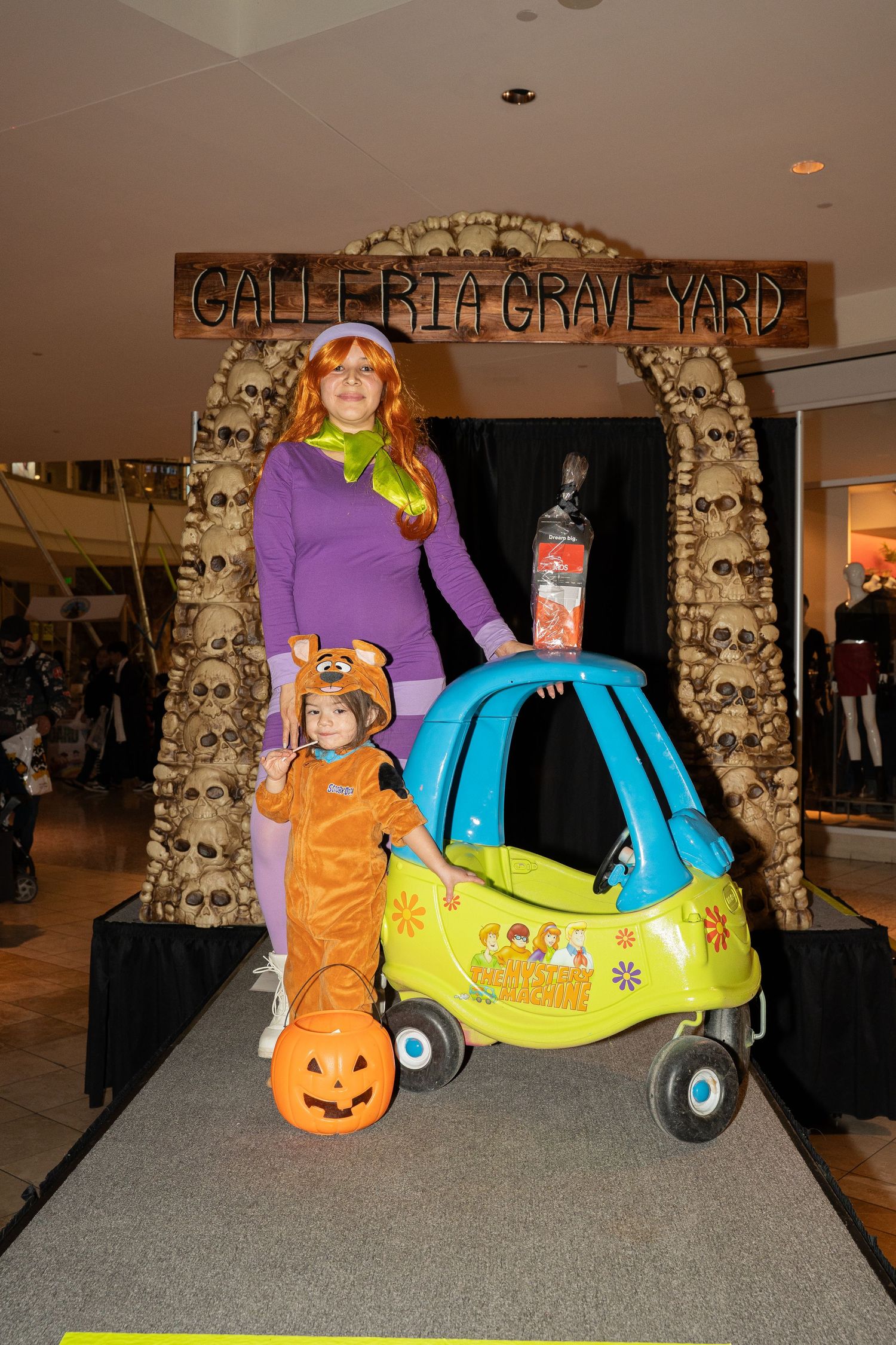 Colorful Halloween display featuring pumpkins, costumes and a decorative scooter.