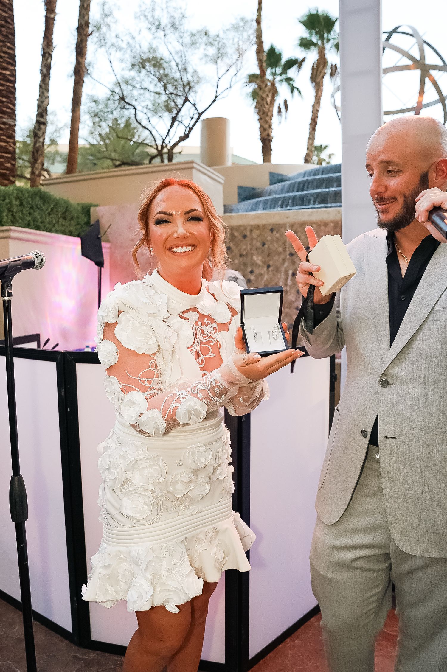 Wedding celebration on outdoor terrace with palm trees in background.