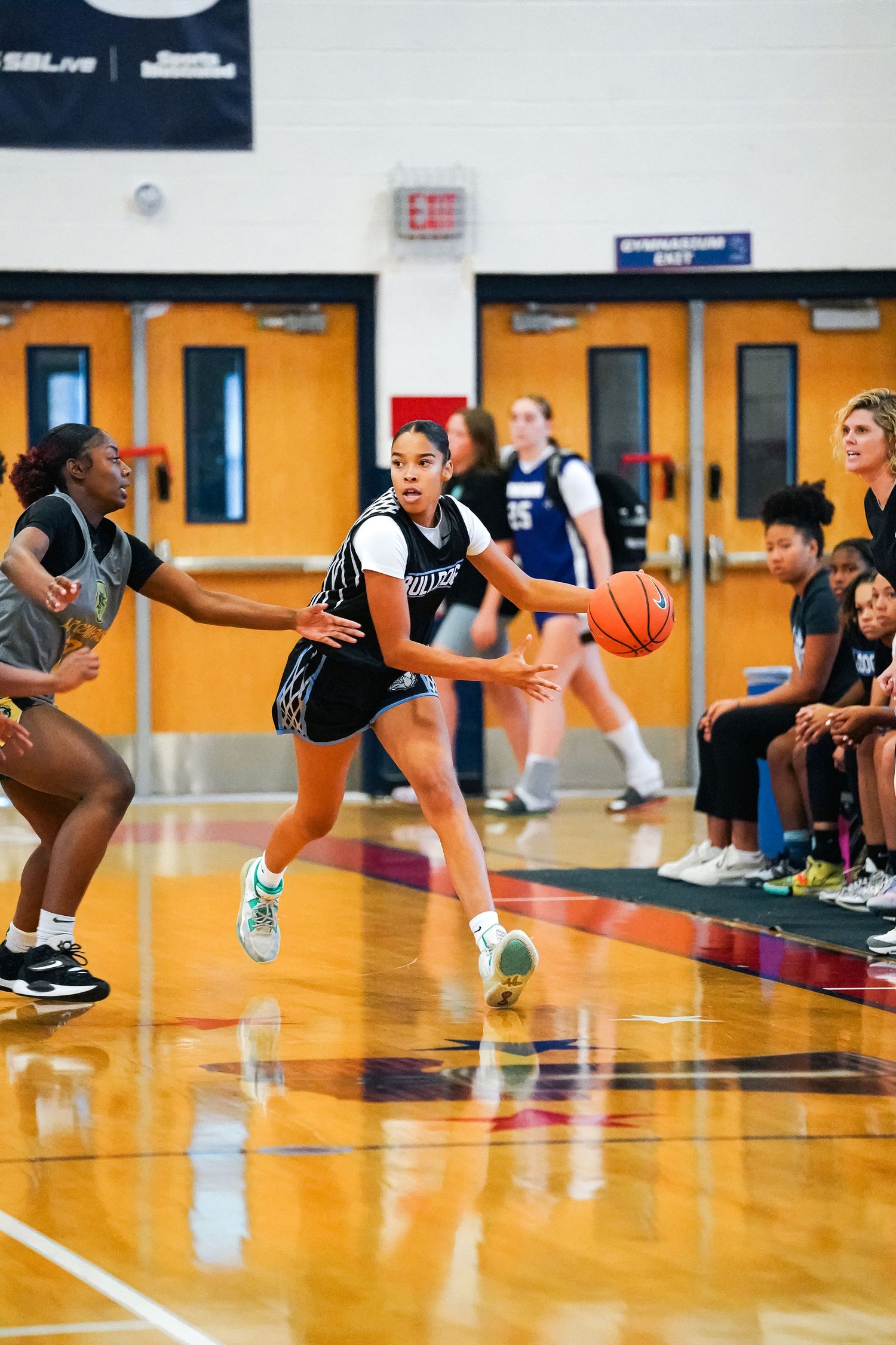 Player drives to basket during competitive basketball game on indoor court.