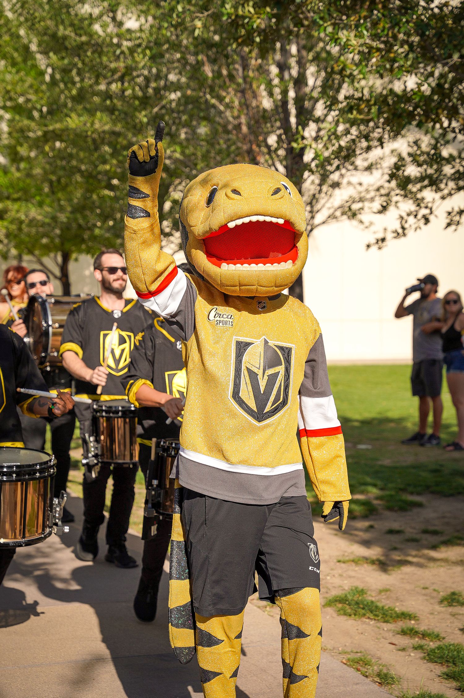 Vegas Golden Knights mascot Chance the Gila Monster poses enthusiastically at an outdoor event.