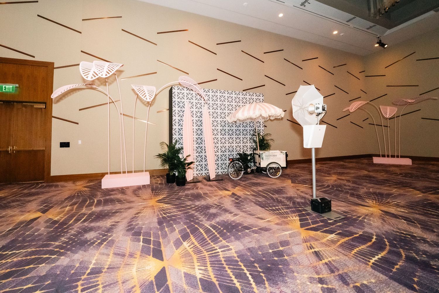 Modern event space with geometric ceiling details and white sculptural elements on patterned carpet.