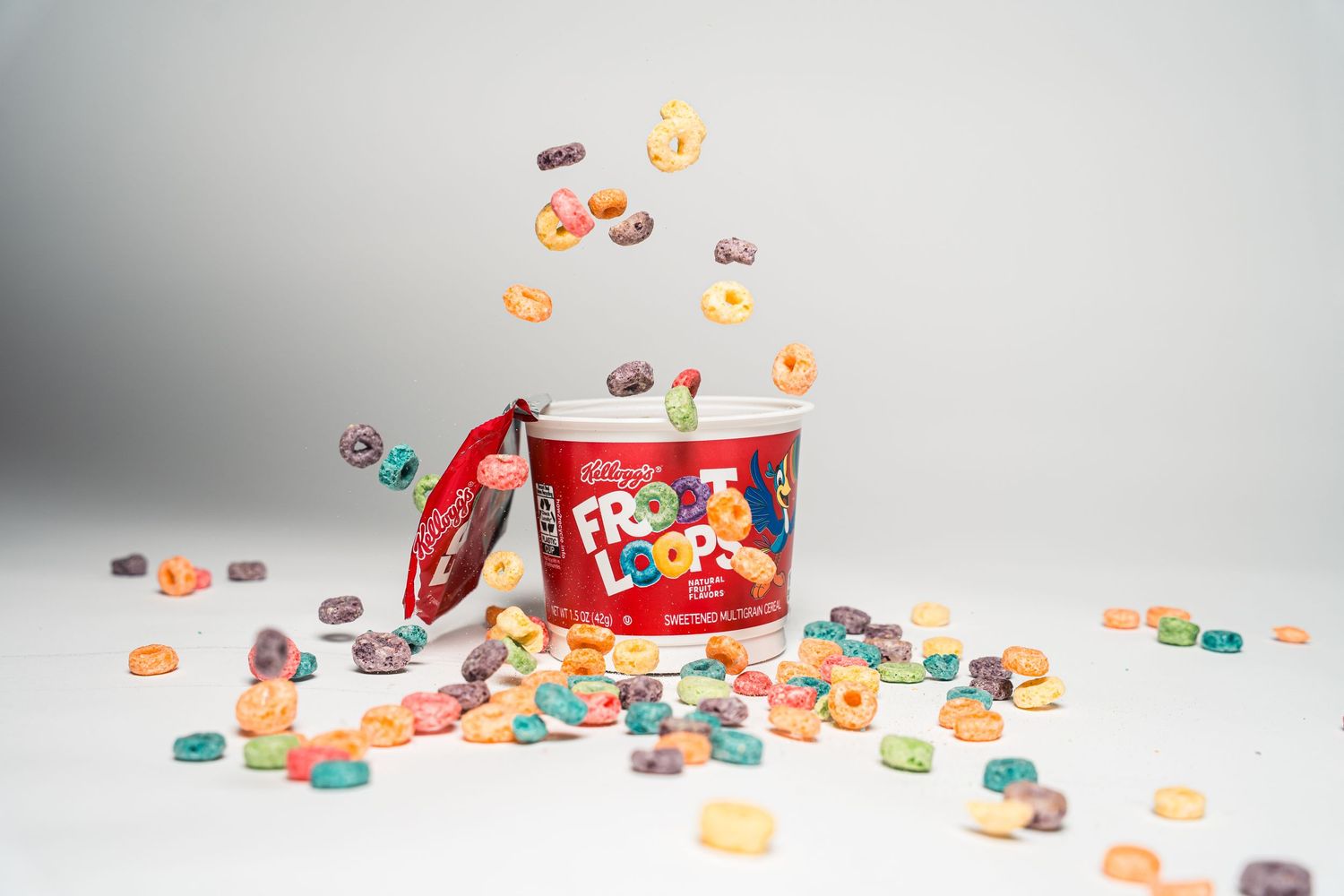 Colorful candy hearts spilling out of a red container against a white background.