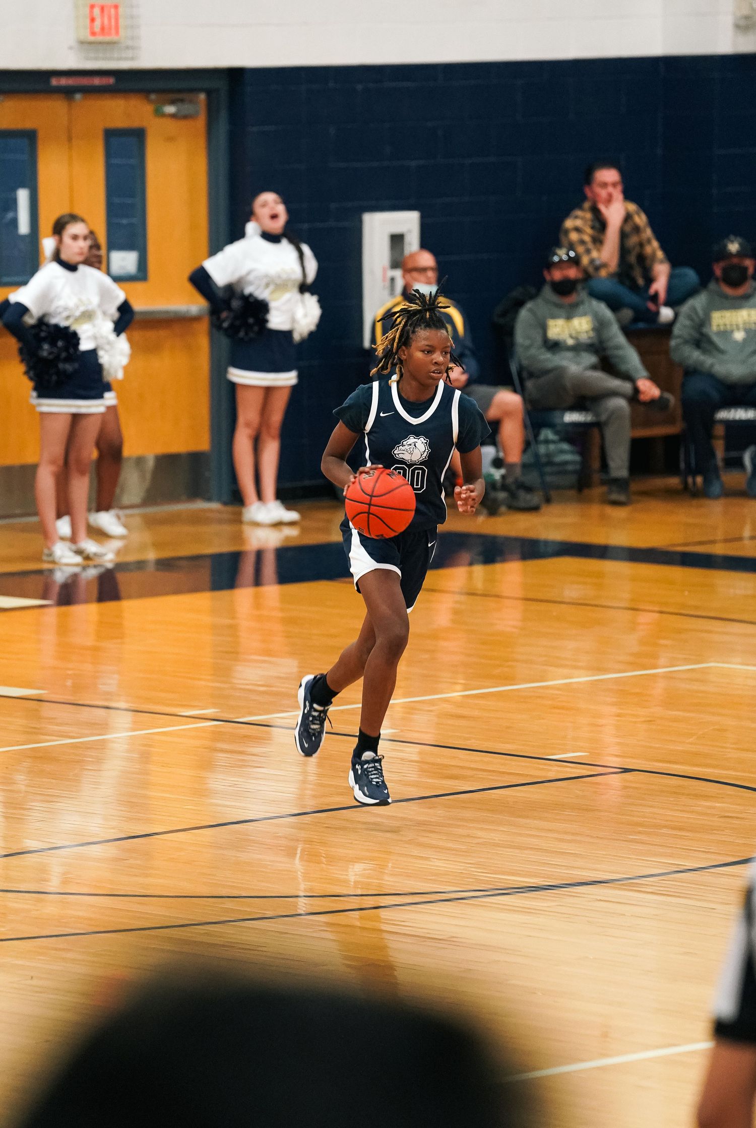 Basketball player dribbles across shiny wooden court during fast break.