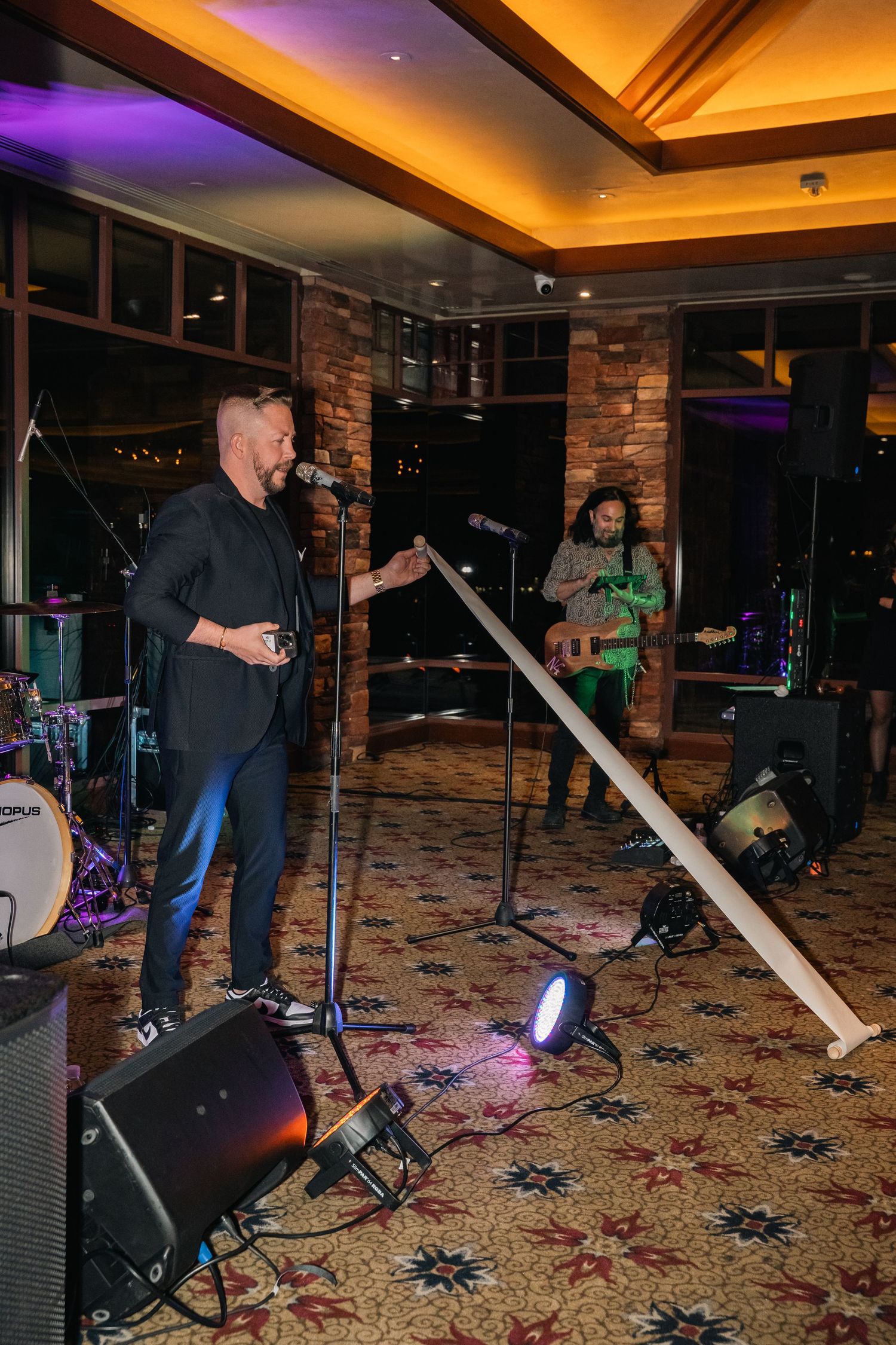 Band performing on stage with instruments at an indoor venue with mood lighting.