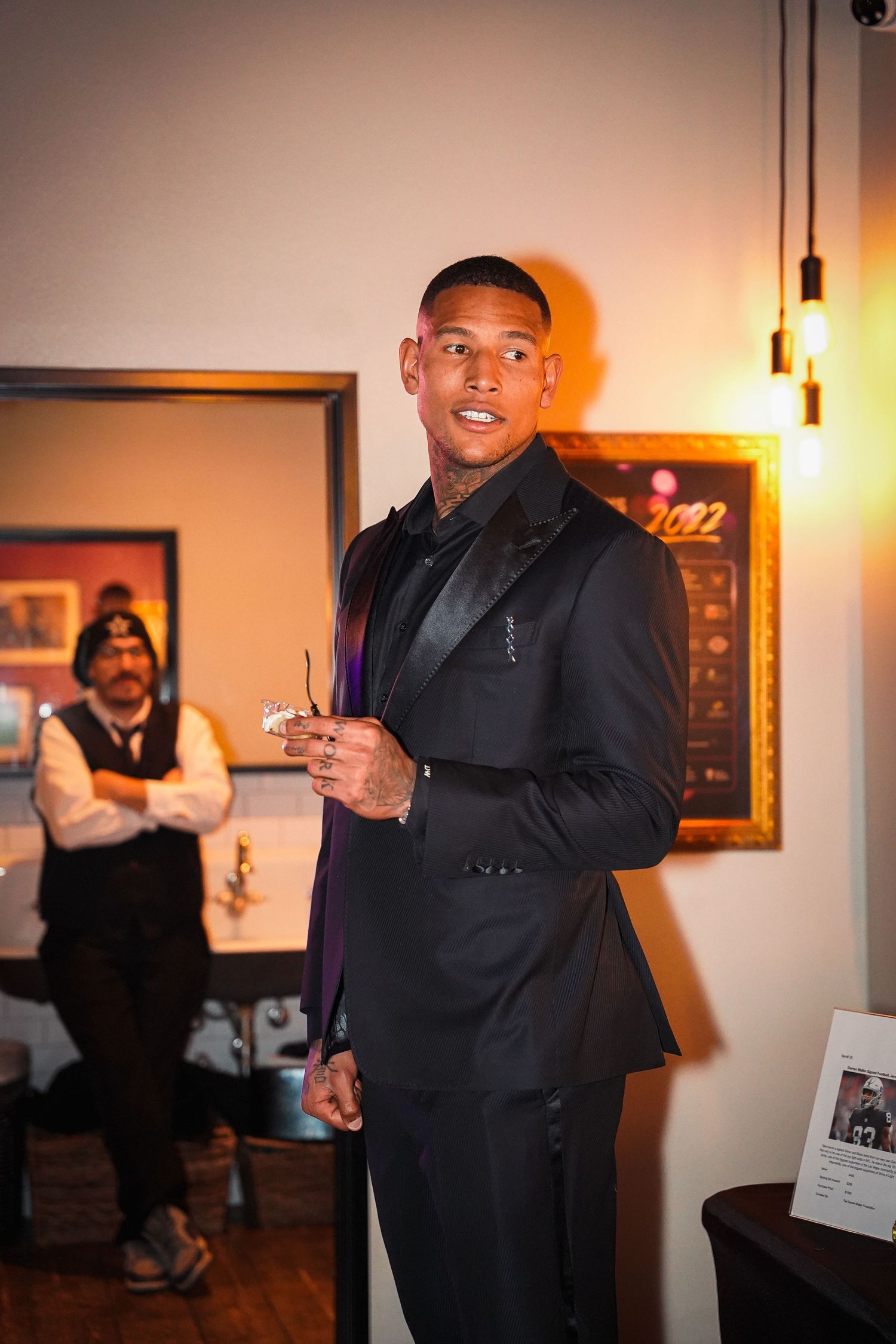 Well-dressed man speaks at evening event under ambient lighting.