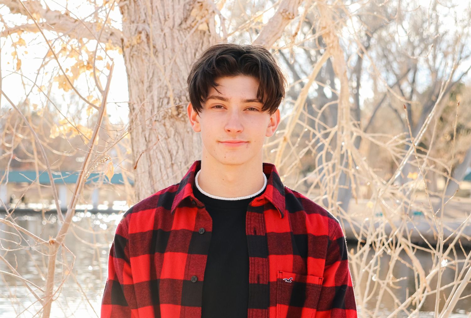 Portrait in red and black plaid flannel against snowy winter scene.