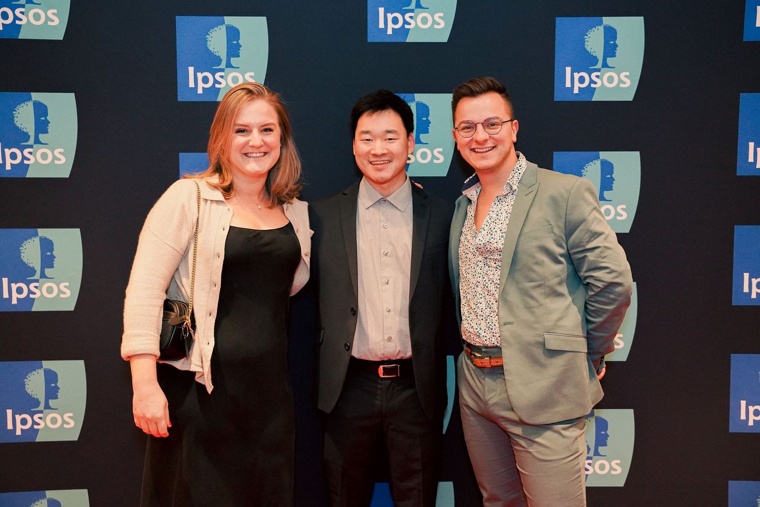 Group photo of professionals at an Ipsos corporate event against branded backdrop.