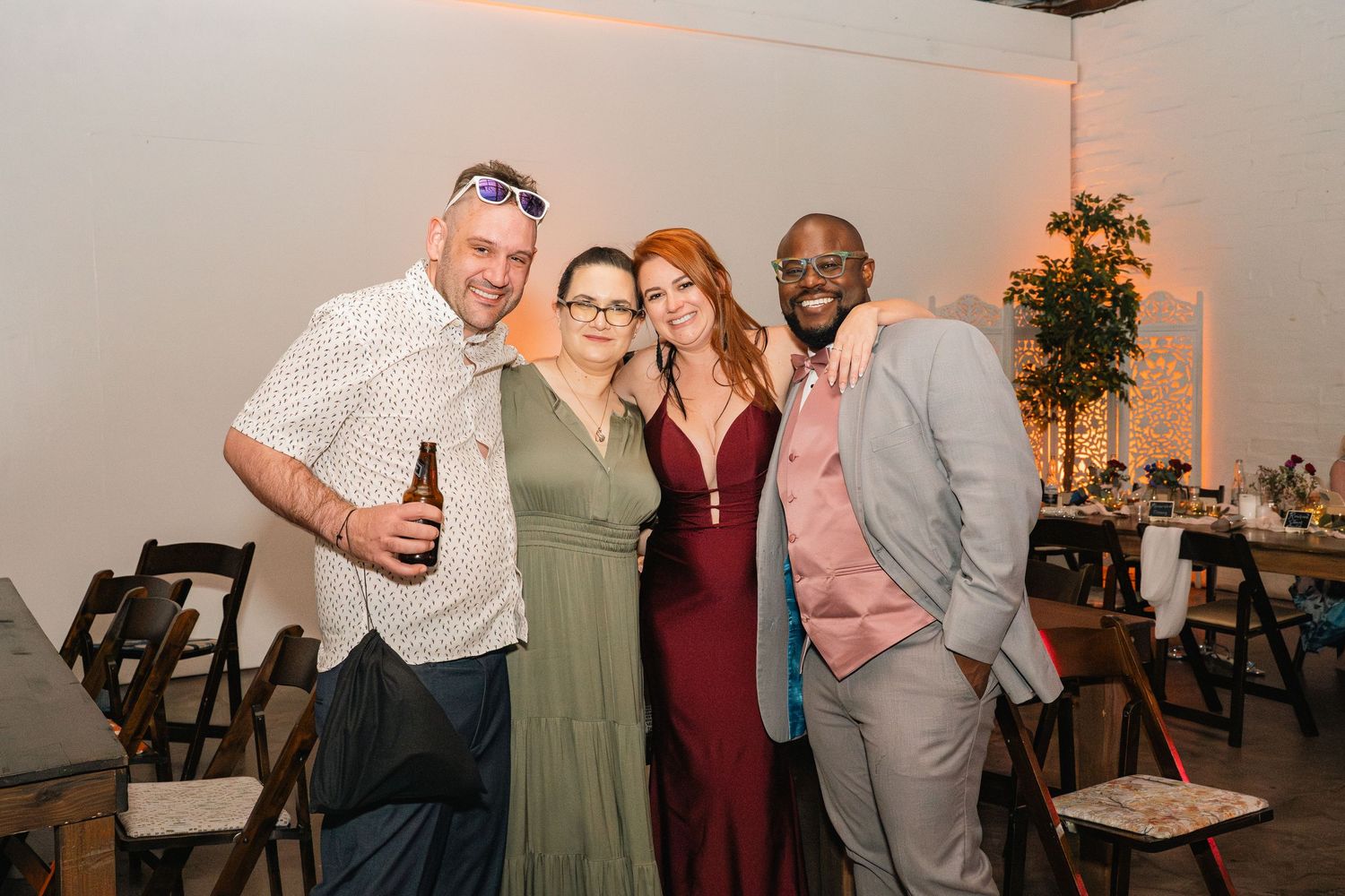 Small group of wedding guests pose together at reception in formal attire.