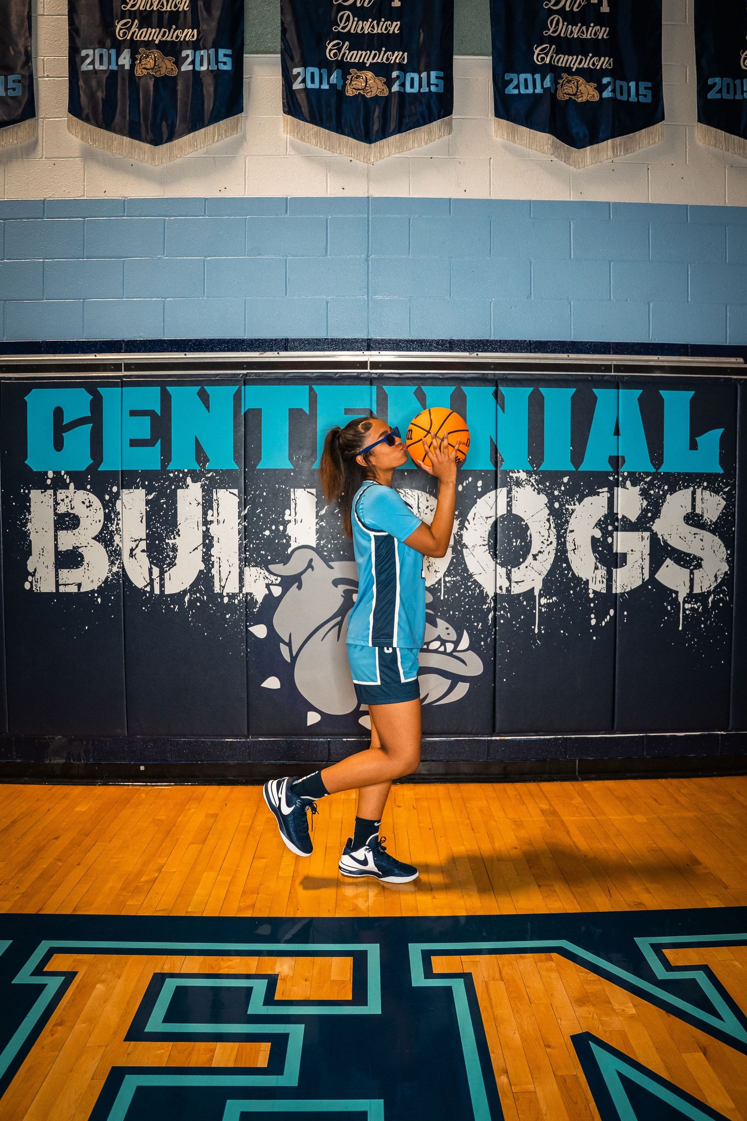 Player demonstrating basketball dribbling skills against themed school wall background.