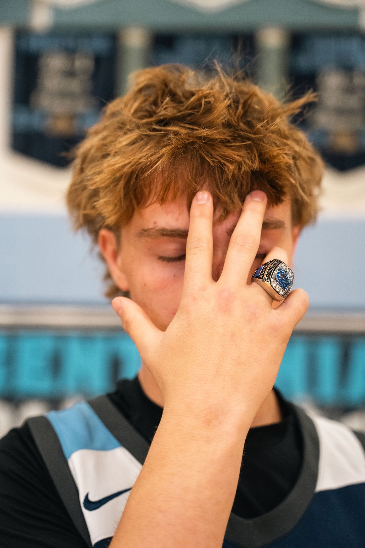Close up of player with messy hair showing championship ring against banner background.