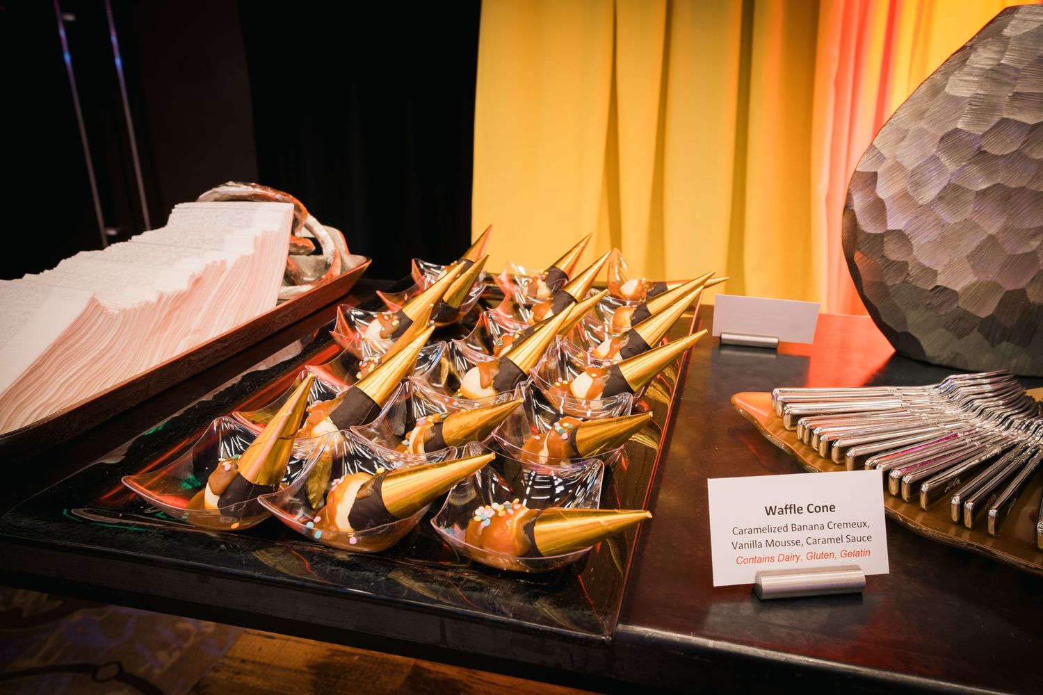 Gourmet sandwich bites arranged neatly on black serving tray with descriptive place card.