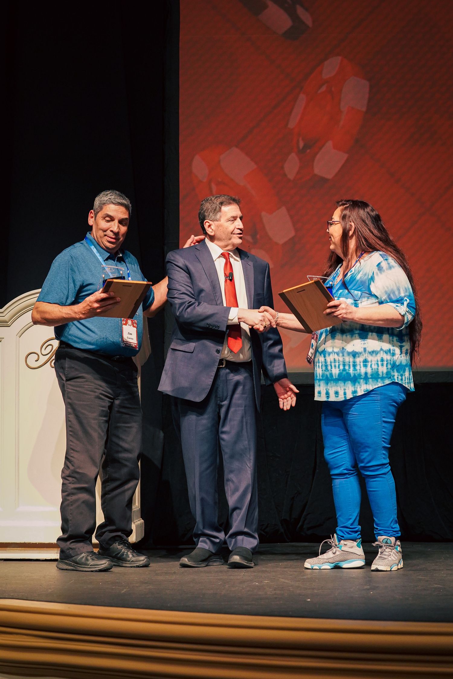 People exchanging items on stage during a presentation ceremony.