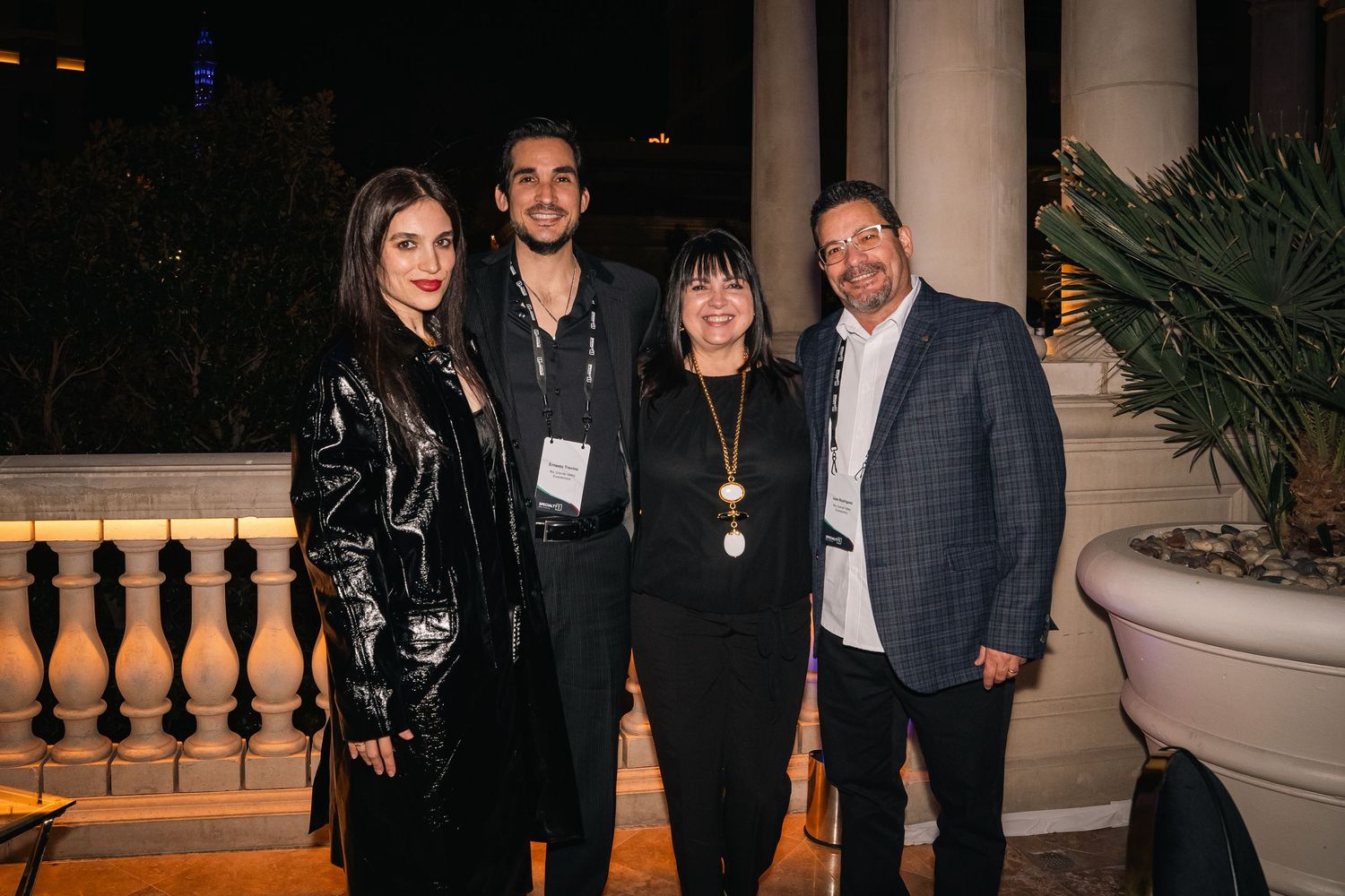 Group of guests pose together at an upscale evening business event with classical architecture.