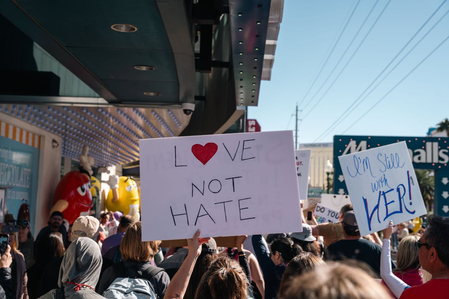 Crowd of protesters holding signs including one that reads 'Love Not Hate' during a demonstration.