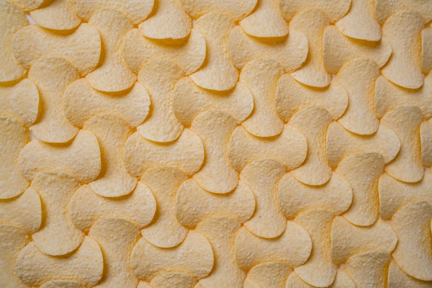 Close-up pattern of repeating yellow curved shapes on a textured surface.