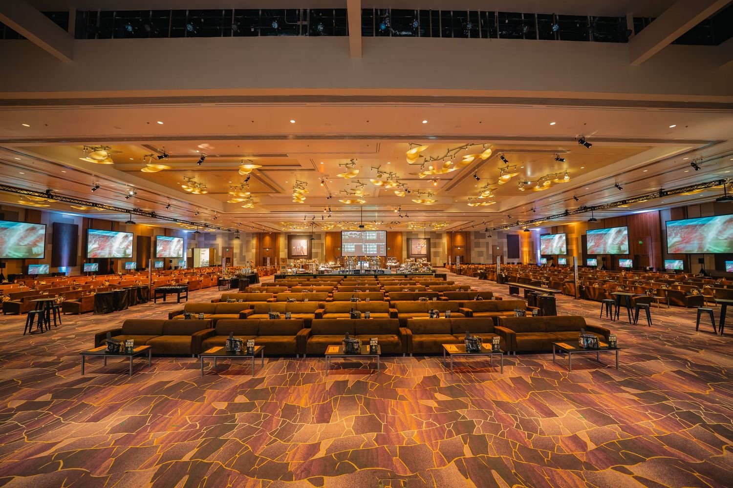 Wide view of a casino gaming floor with rows of slot machines and dramatic ceiling lighting.