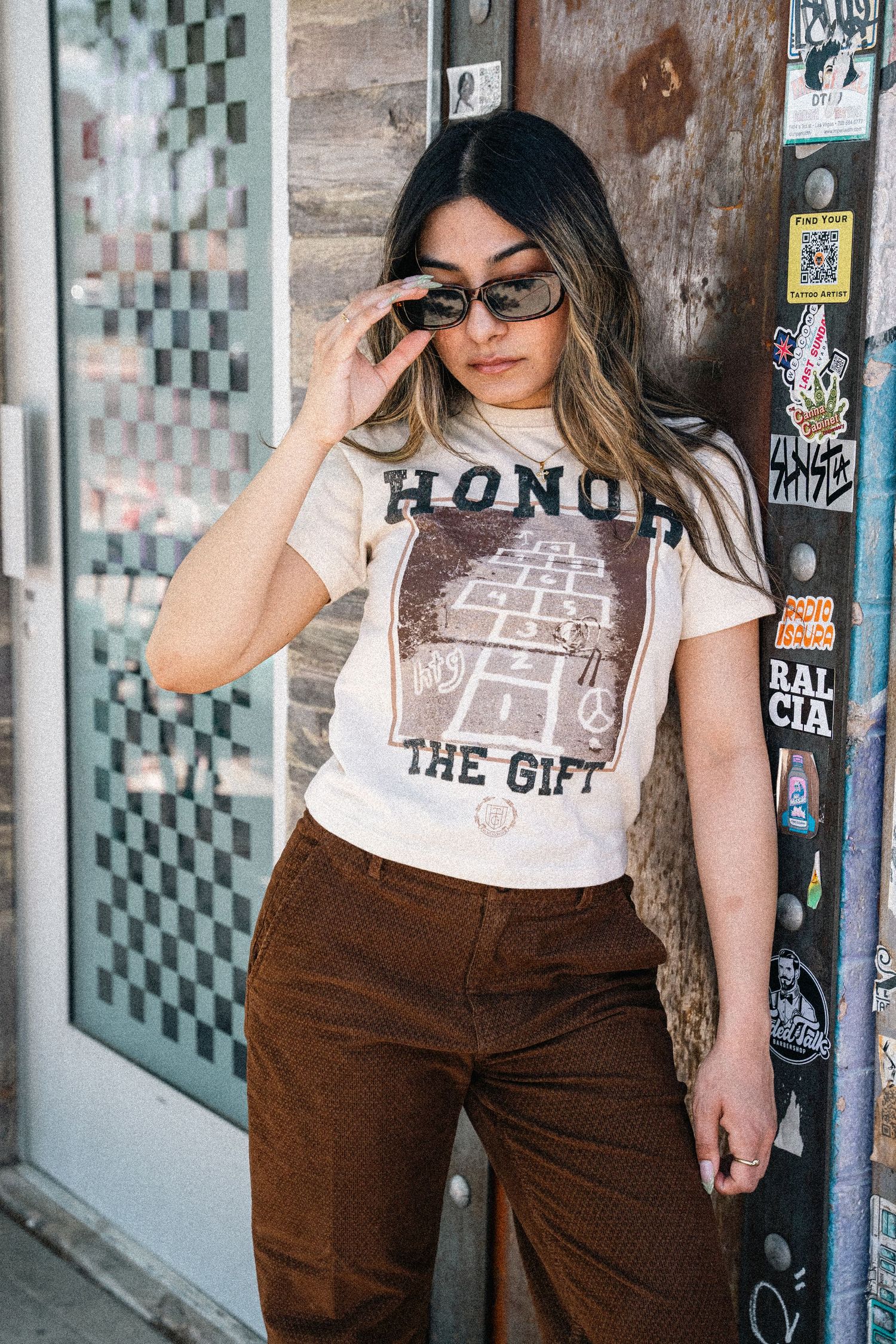 Urban fashion shots showing graphic t-shirt and brown pants against graffiti wall.