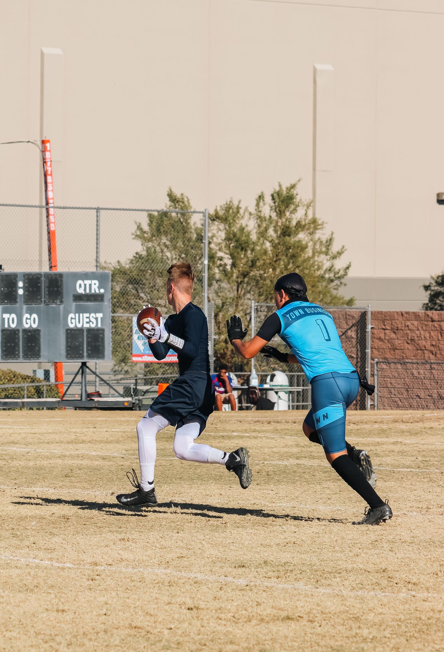 Players in red and blue uniforms compete during an outdoor flag football game on a grass field.