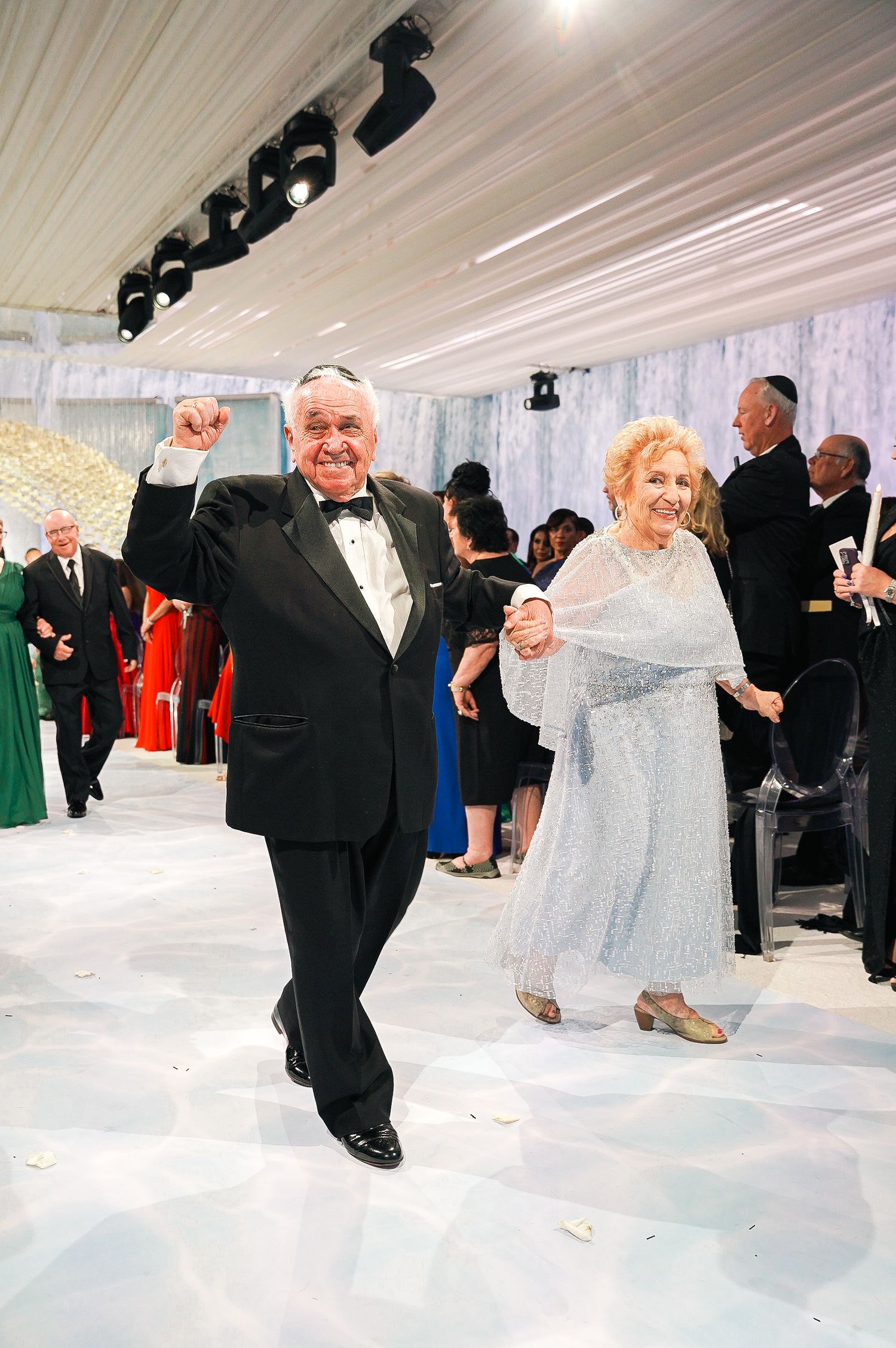 An elderly couple dances joyfully at a formal event.