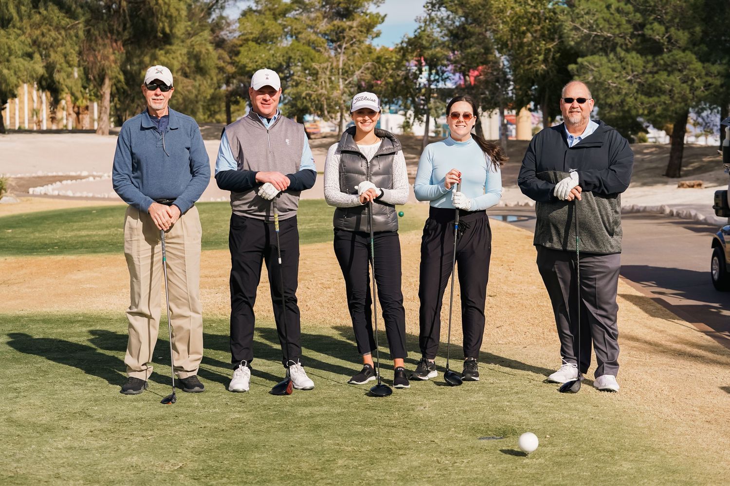 Group of golfers posing together on a desert golf course fairway.