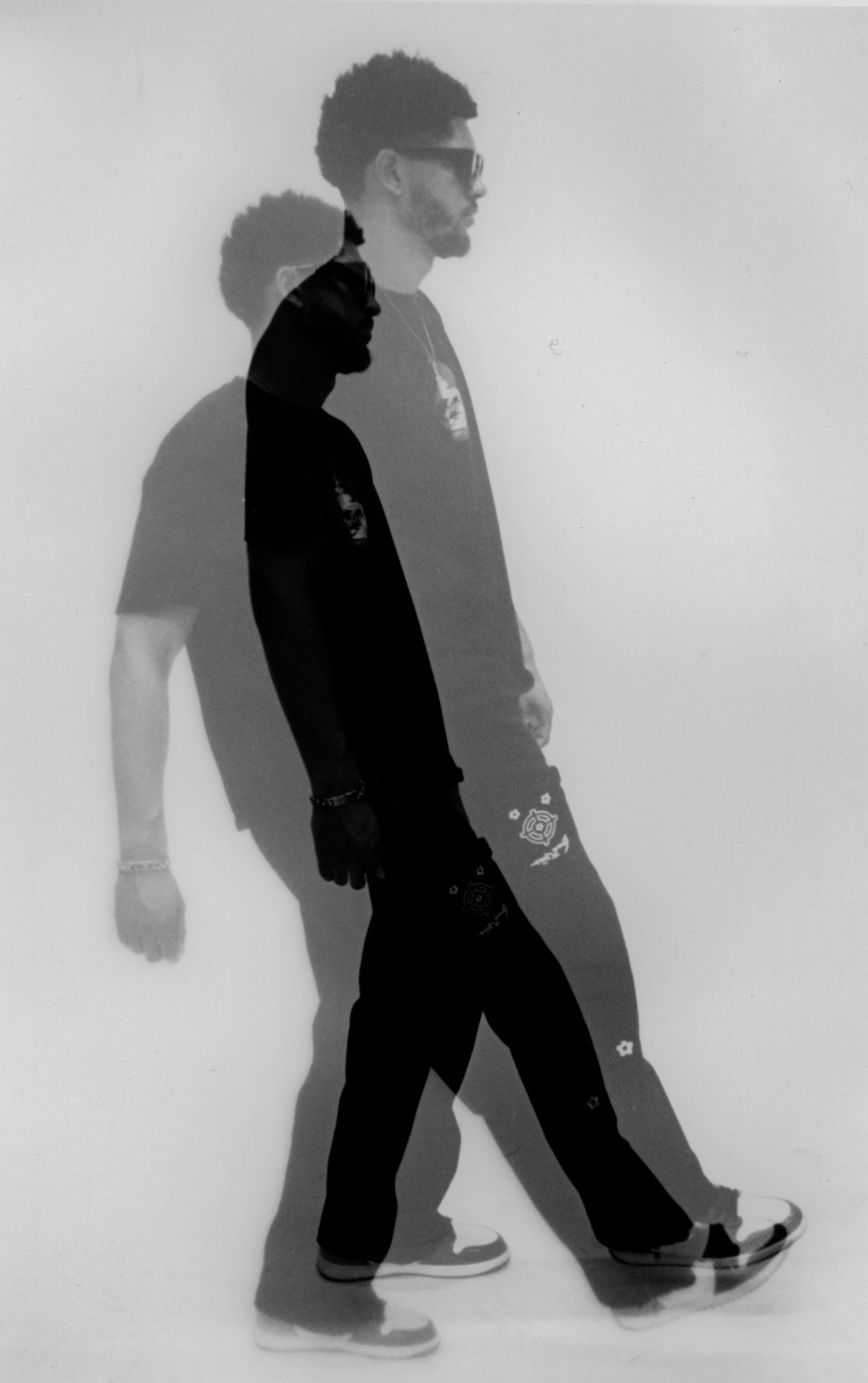 Artistic black and white silhouette of person walking with dramatic shadow cast on wall.