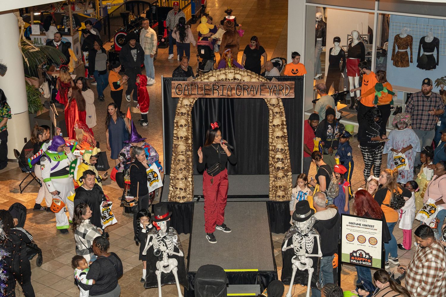 Large crowd gathered around a decorated archway during a Halloween event at a shopping center.