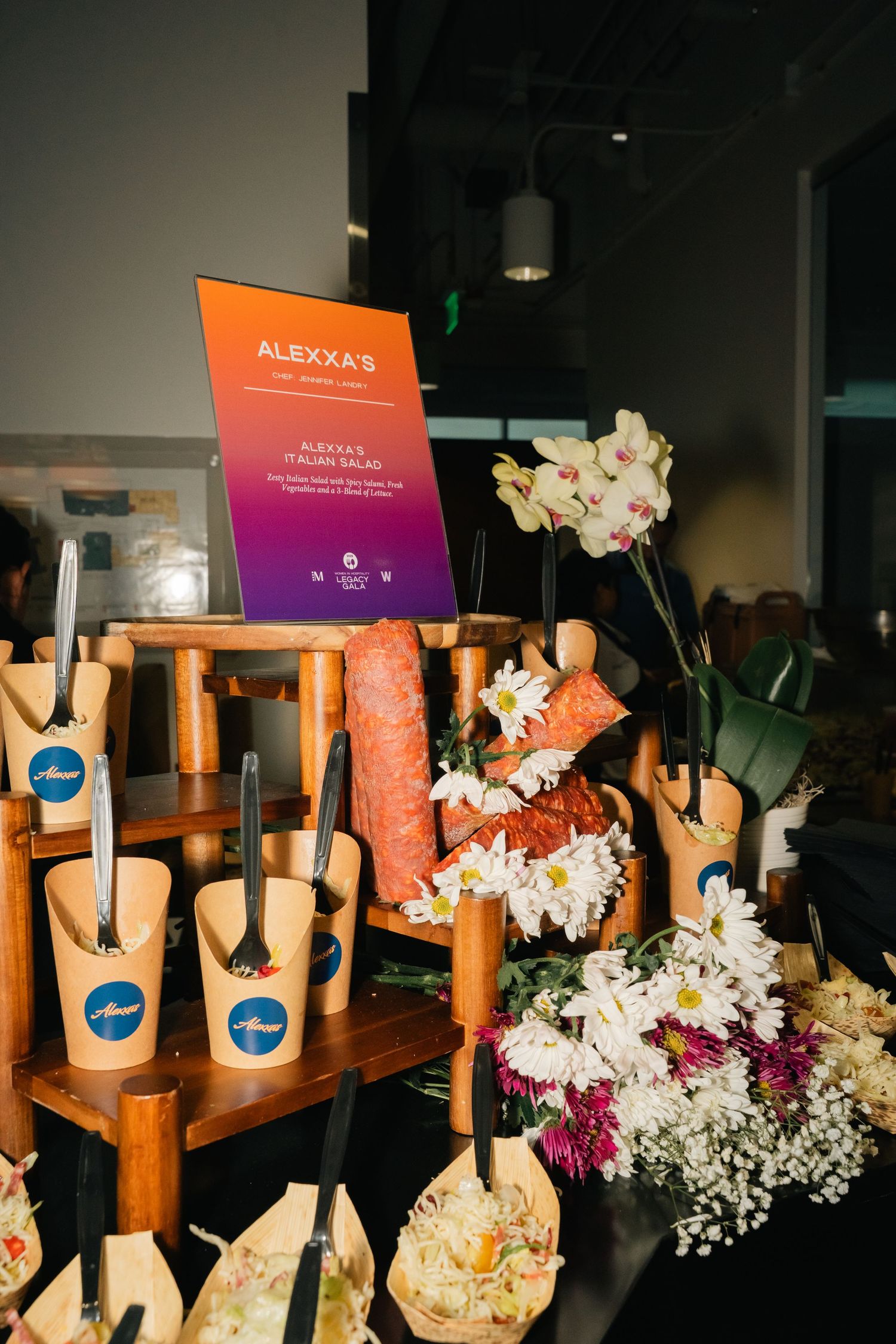 Wooden display stands decorated with white orchids and colorful signage at an event.