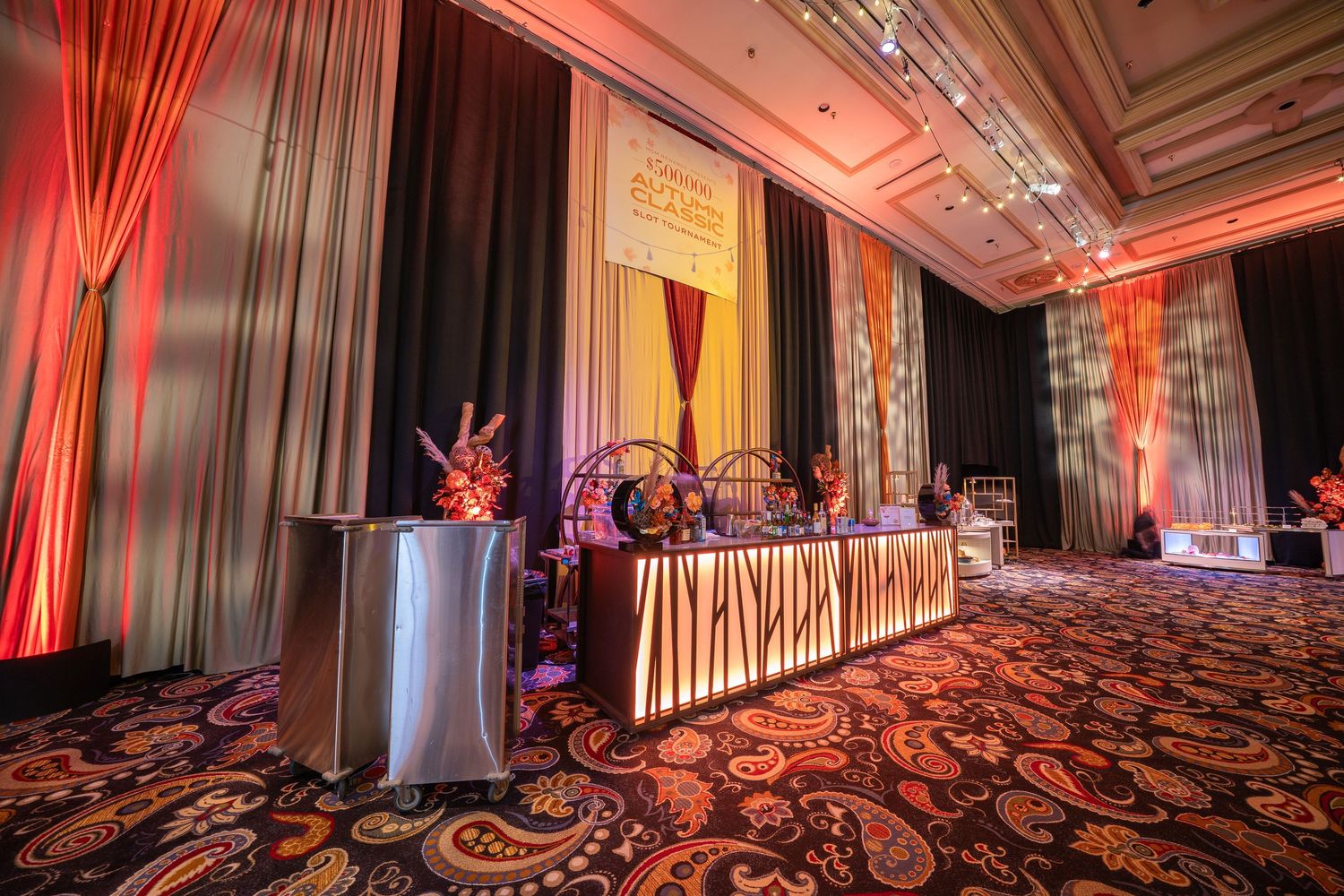 Elegant ballroom setup with red ambient lighting and white curtains along the walls.