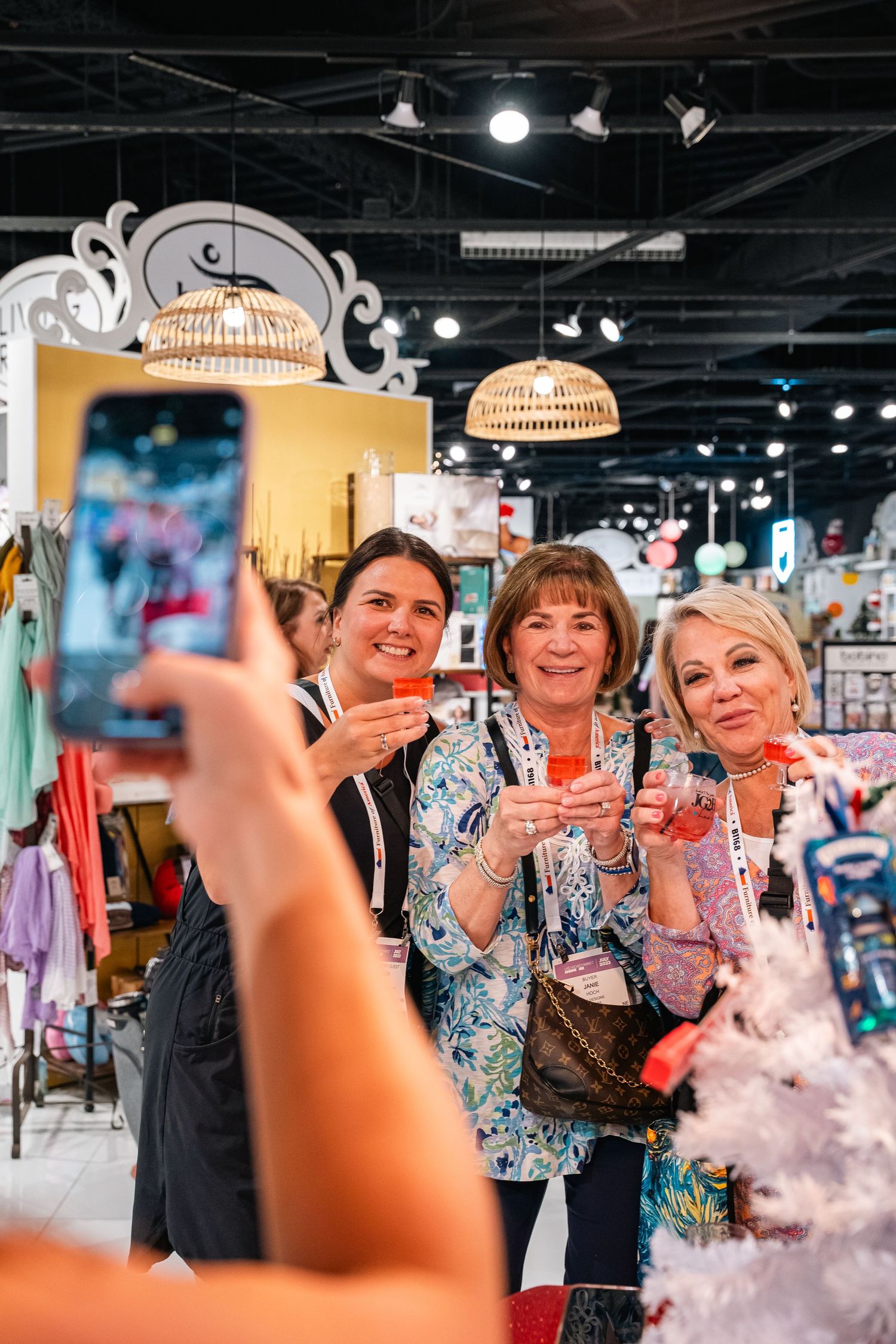 People taking celebratory drinks at retail store event with decorative lighting.