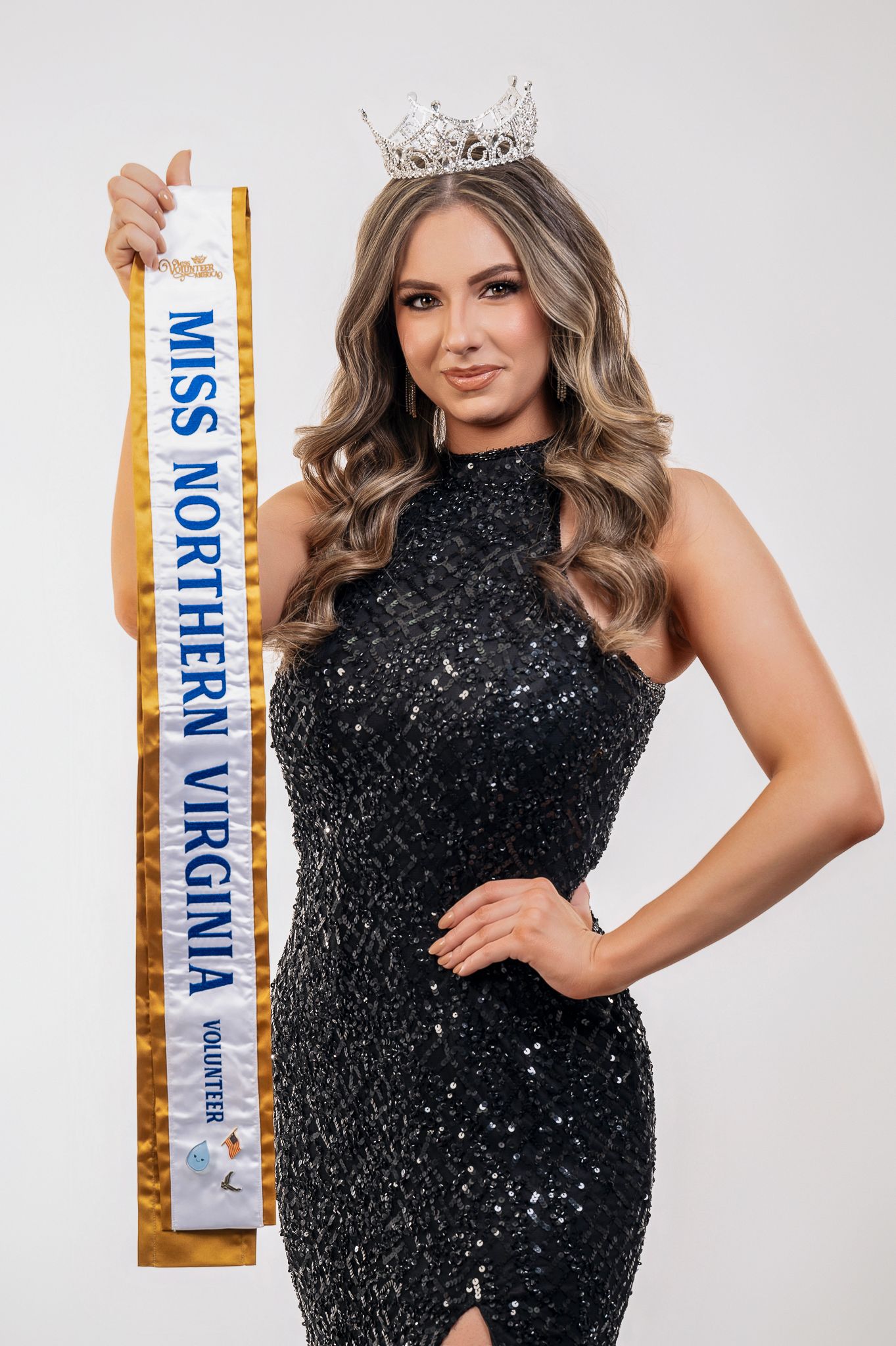 A pageant contestant wearing a sparkling black halter dress and crown poses with a sash that reads Miss Northern Virginia.