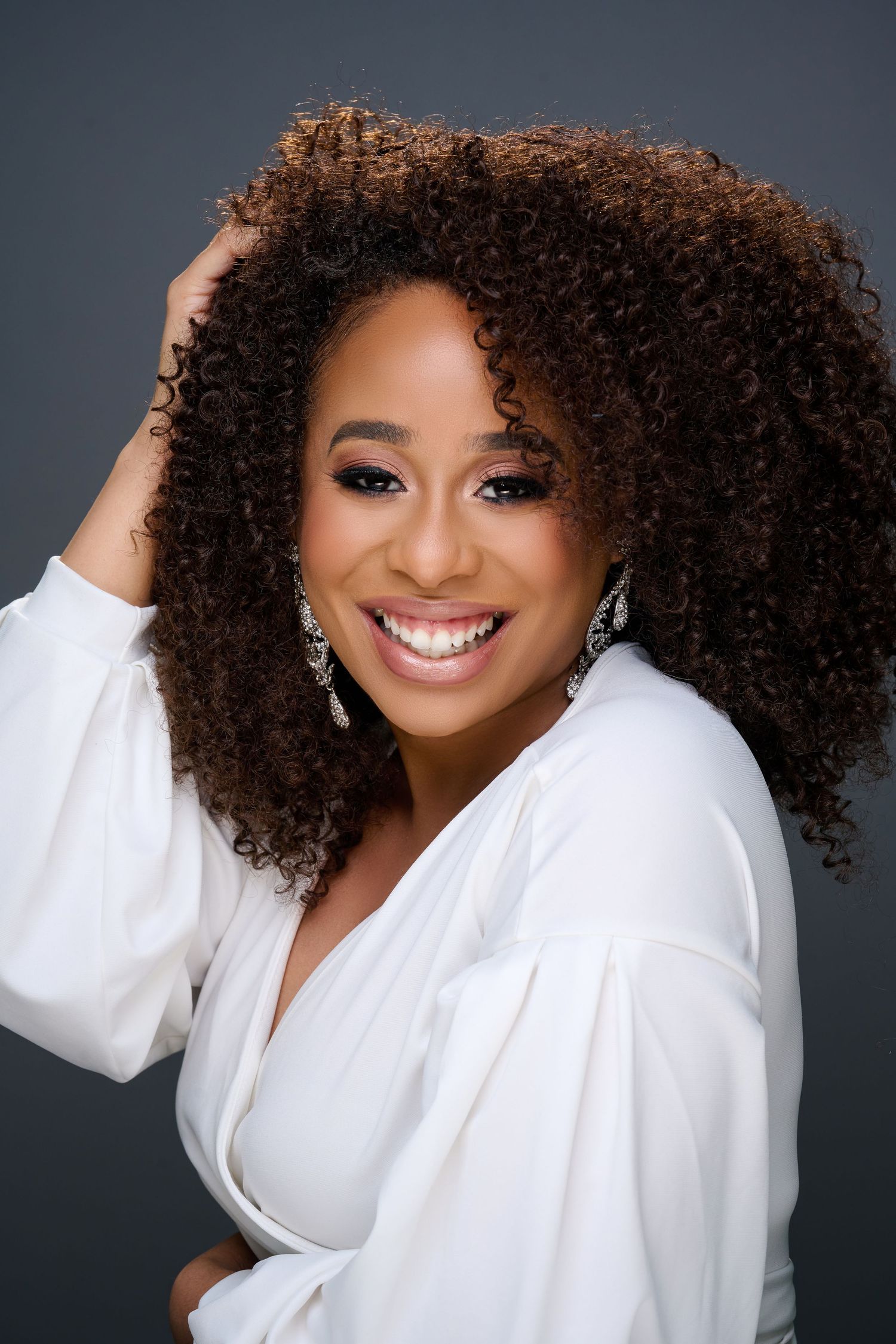 Portrait series showing joyful expressions and natural curly hair against dark background wearing white blouse.