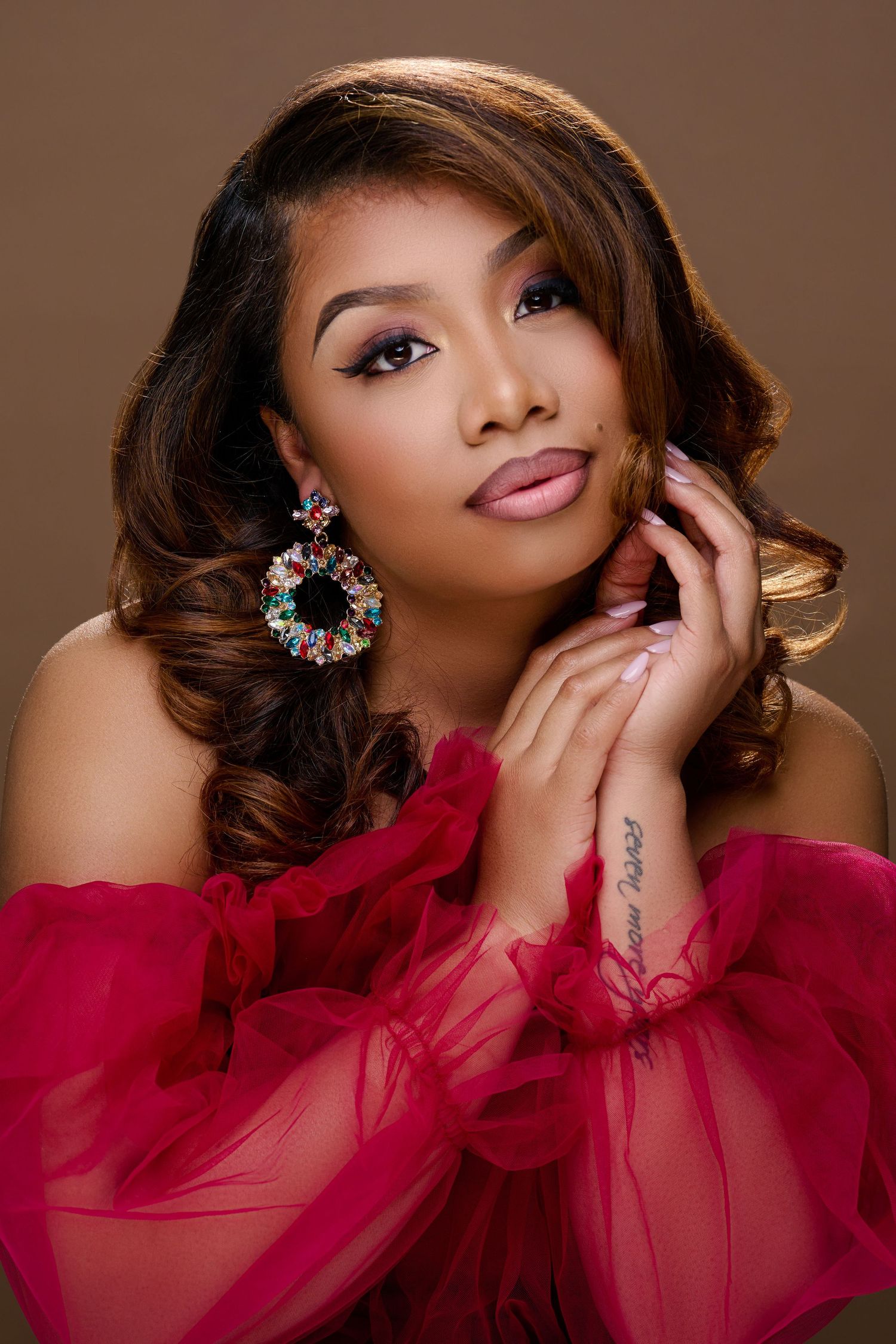 A glamorous portrait series featuring a person in a flowing red tulle gown posing elegantly against a brown backdrop.