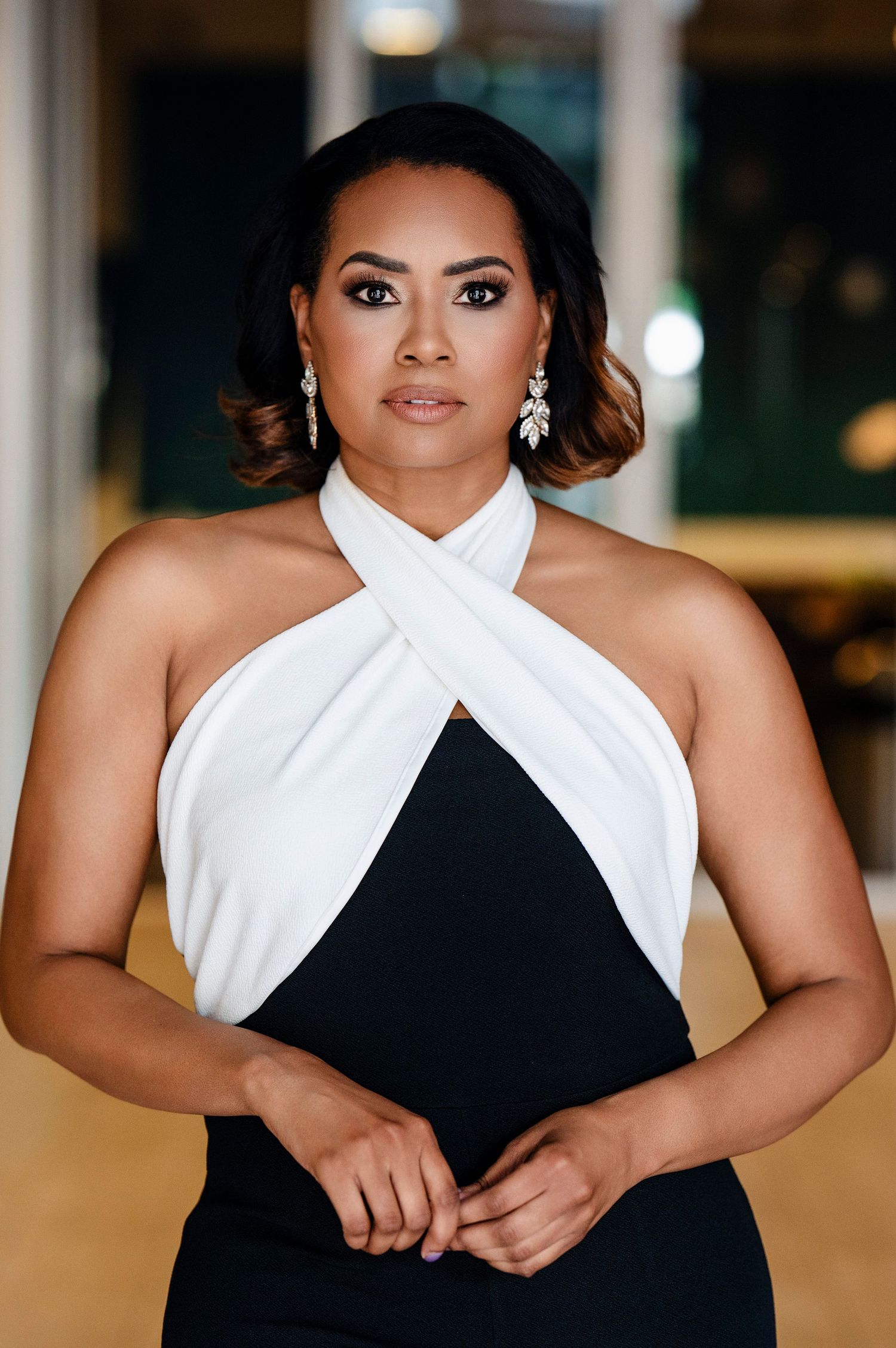 Portrait shot of an elegant woman in a black and white halter dress with crossover neckline and dangling earrings.
