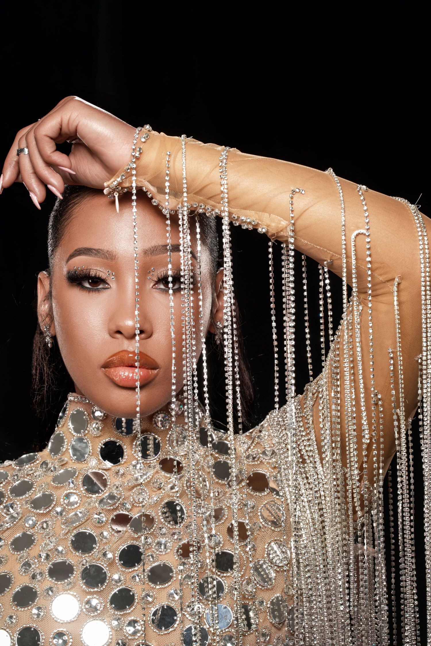 Elegant fashion portrait with draped crystal strands and a sequined high-neck top creating a glamorous look.