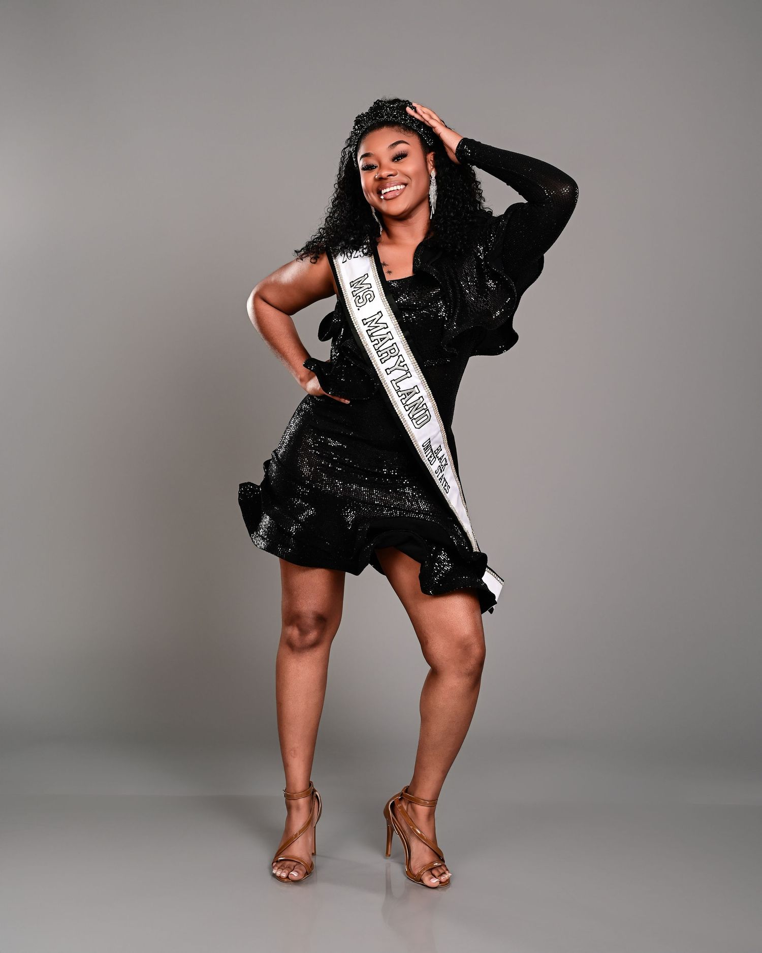 A series of fashion photos showing someone in a sparkly black romper and white sash posing confidently against a gray backdrop.