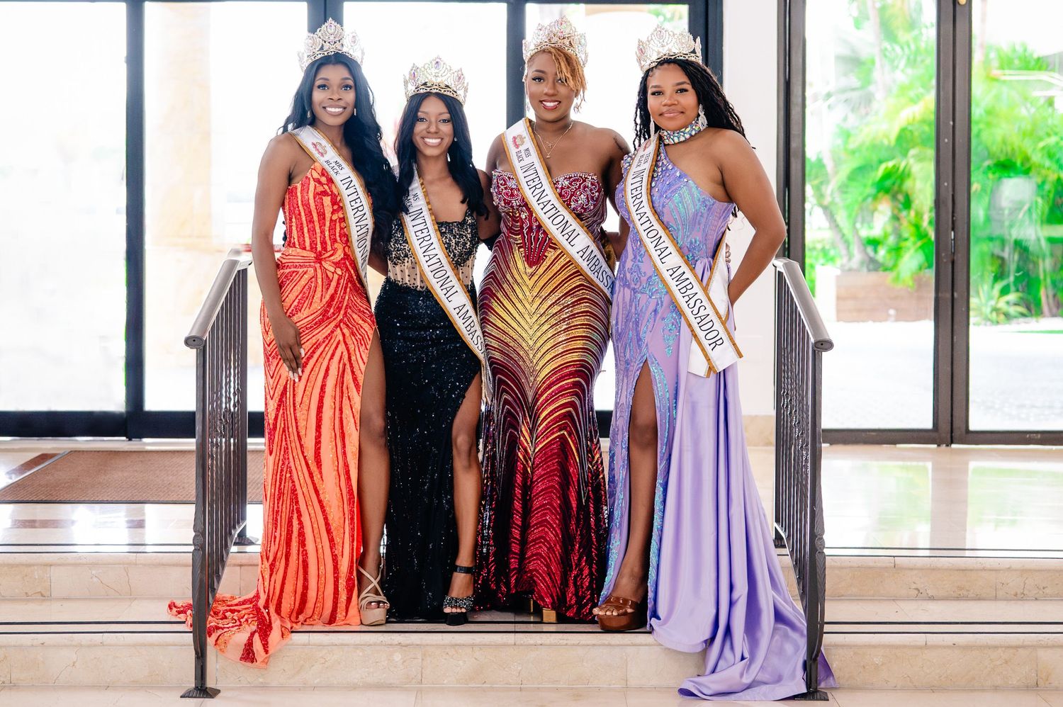 A group of people in formal evening gowns and pageant attire pose together for photos at an event.