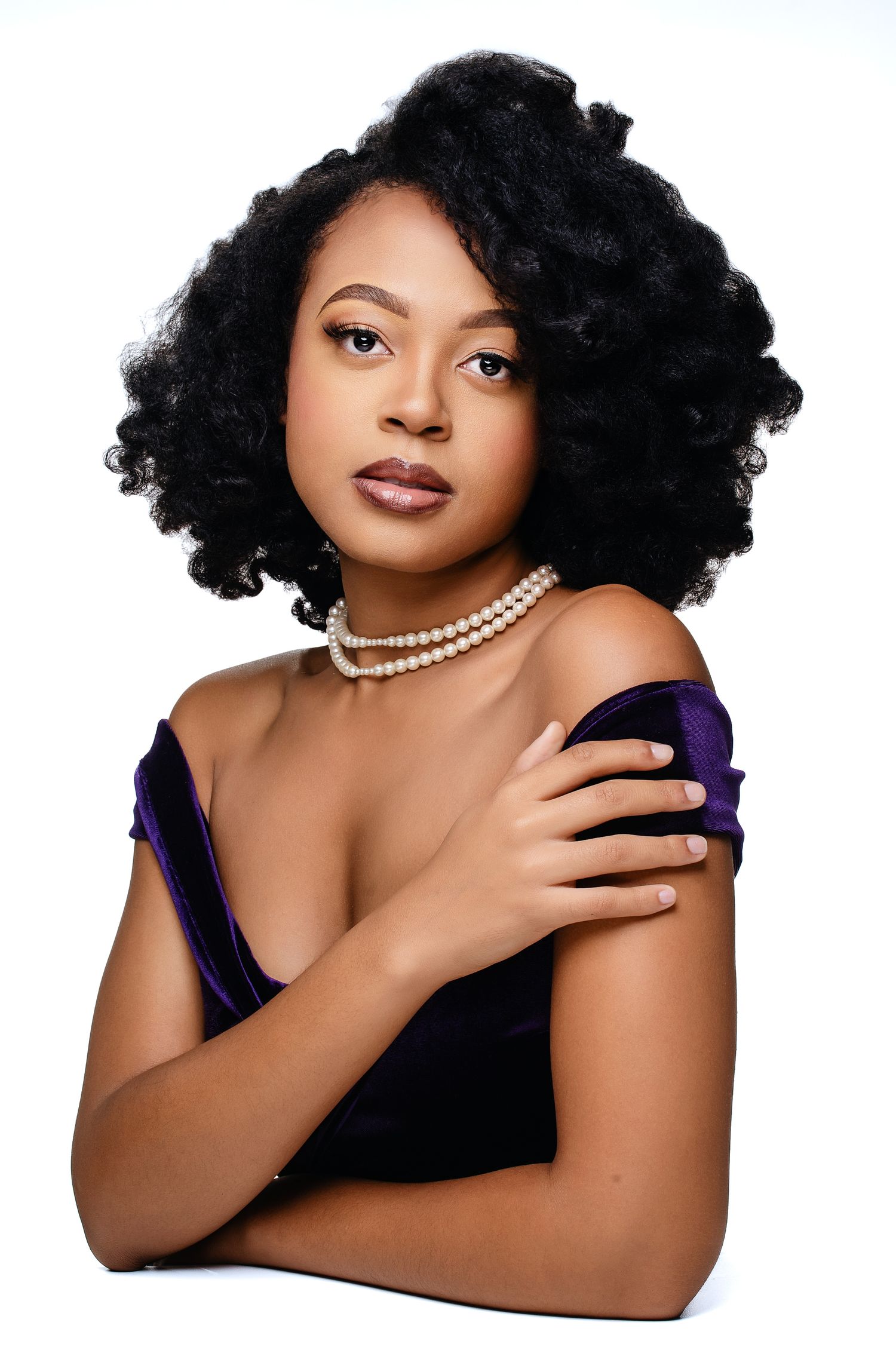 Glamour portrait series showing elegant poses with curly hair, dark lipstick, and pearl necklace against white background.